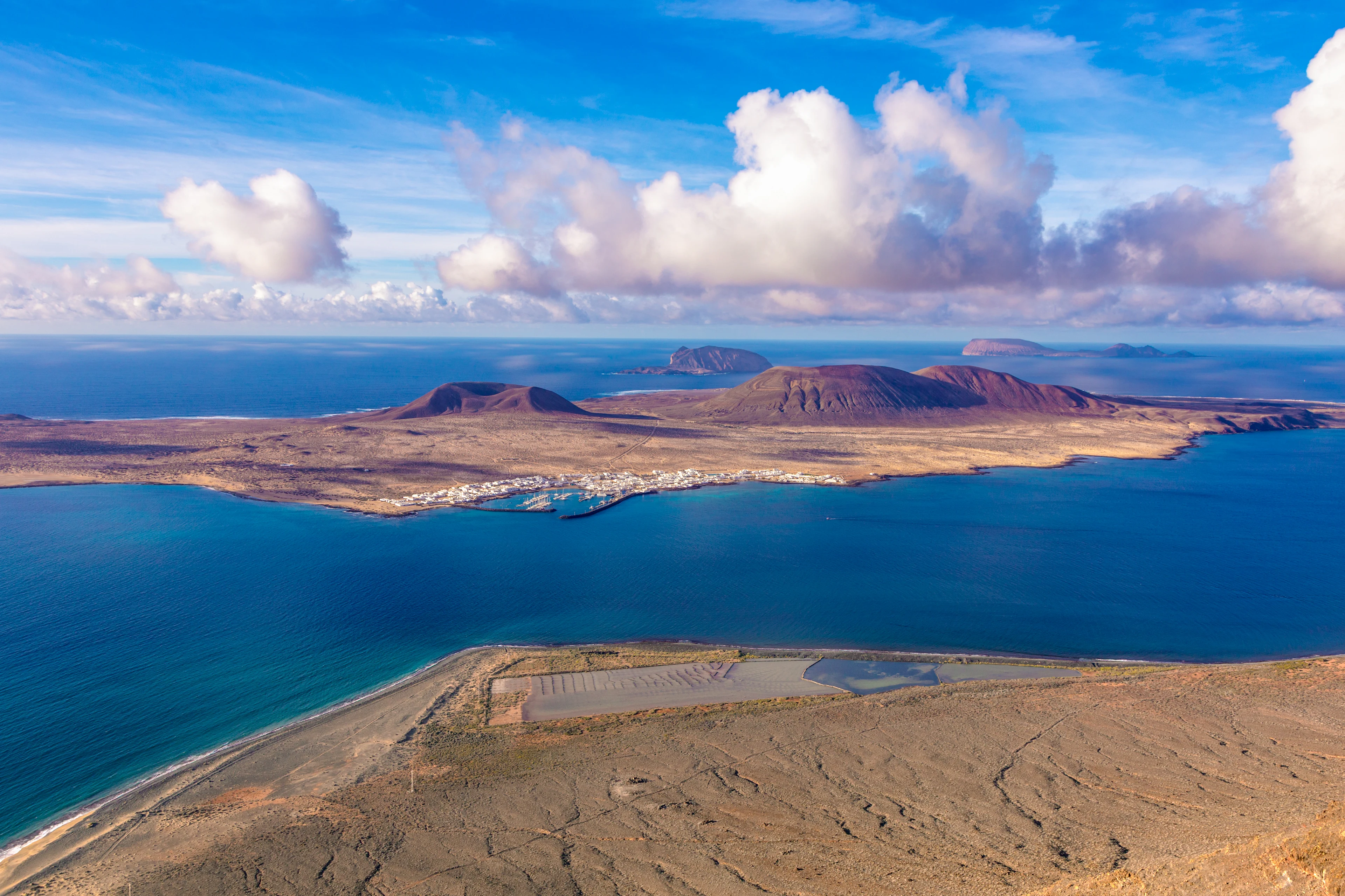 Utsikt över Salinas de Janubio på Lanzarote med saltdammar, vulkaniska kullar och Atlantens blå vatten i bakgrunden.