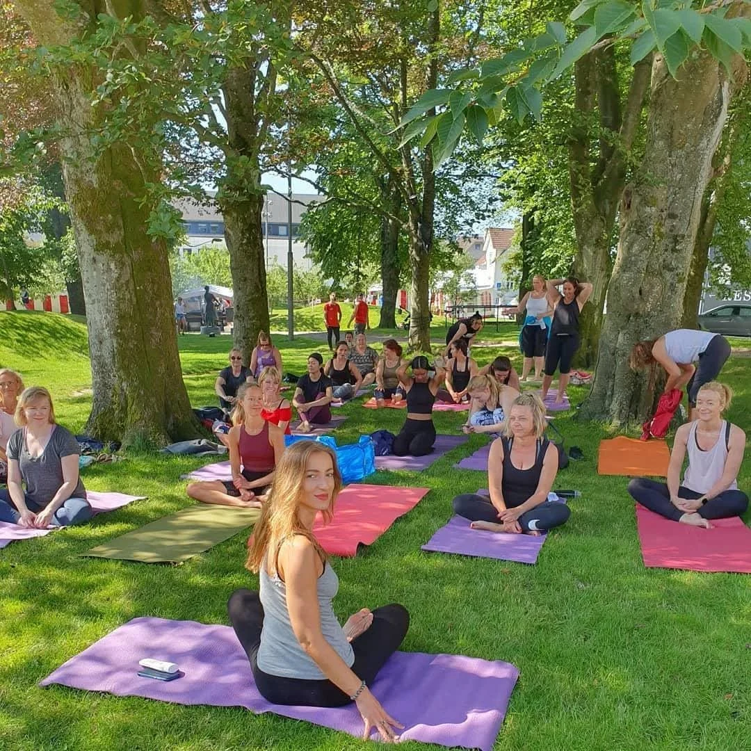 Melisa Nalo som instruerer i yoga under trærne i en park.