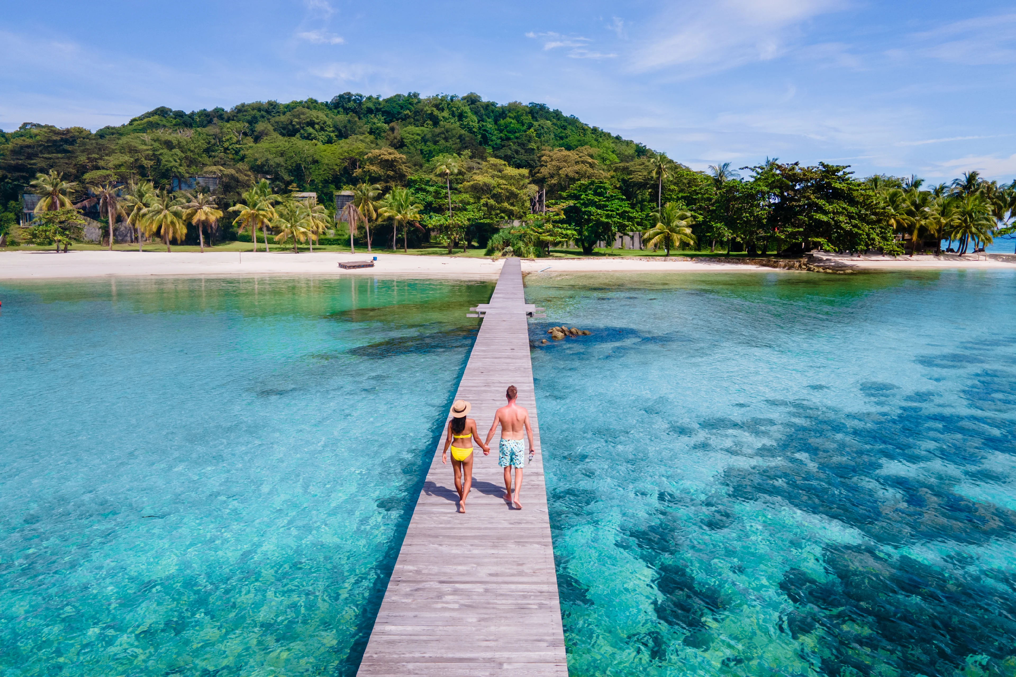 Ett par som promenerar på en brygga vid en strand i Thailand