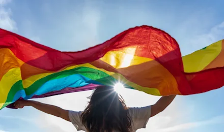 En kvinna med prideflagga i solskenet