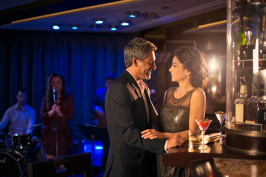 Ett par som står vid en bardisk och ler mot varandra 