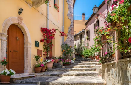 En mysigt gata med färgglada hus och blommor på Sicilien