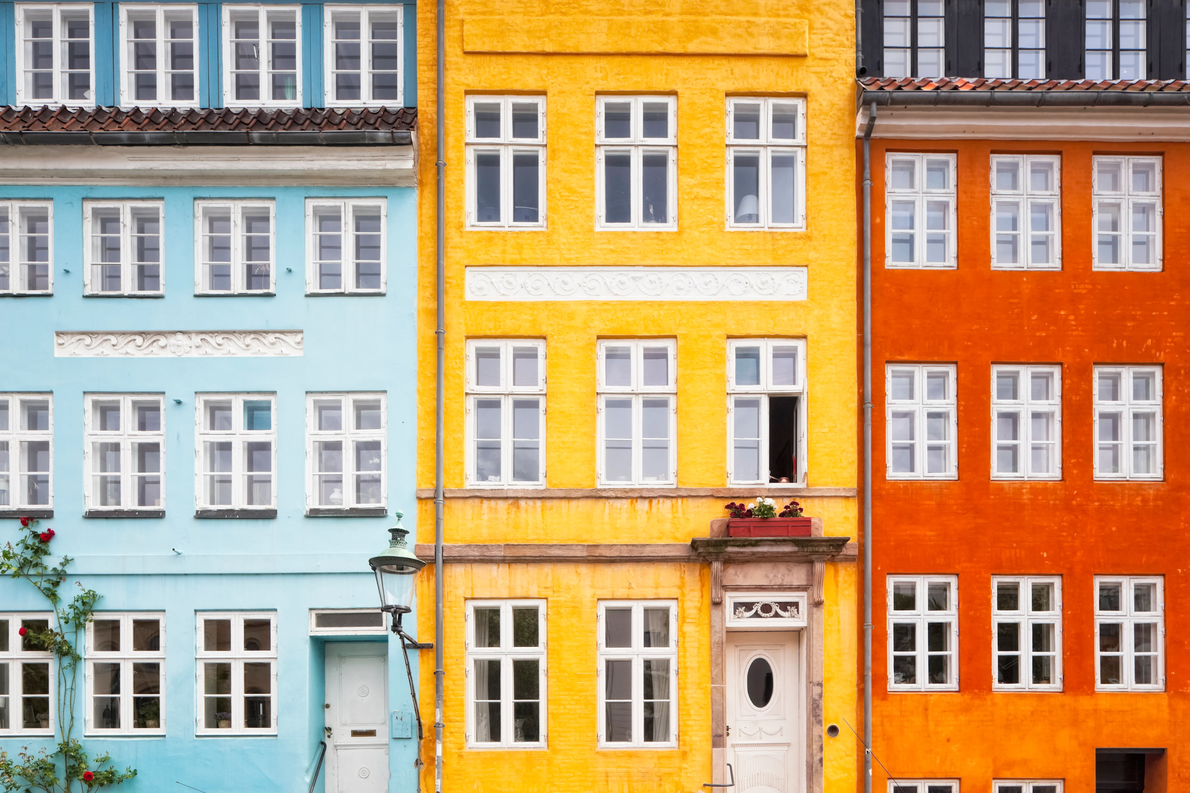 Färgglada stadshus i Köpenhamn med fasader i ljusblått, gult och orange samt vita spröjsade fönster.