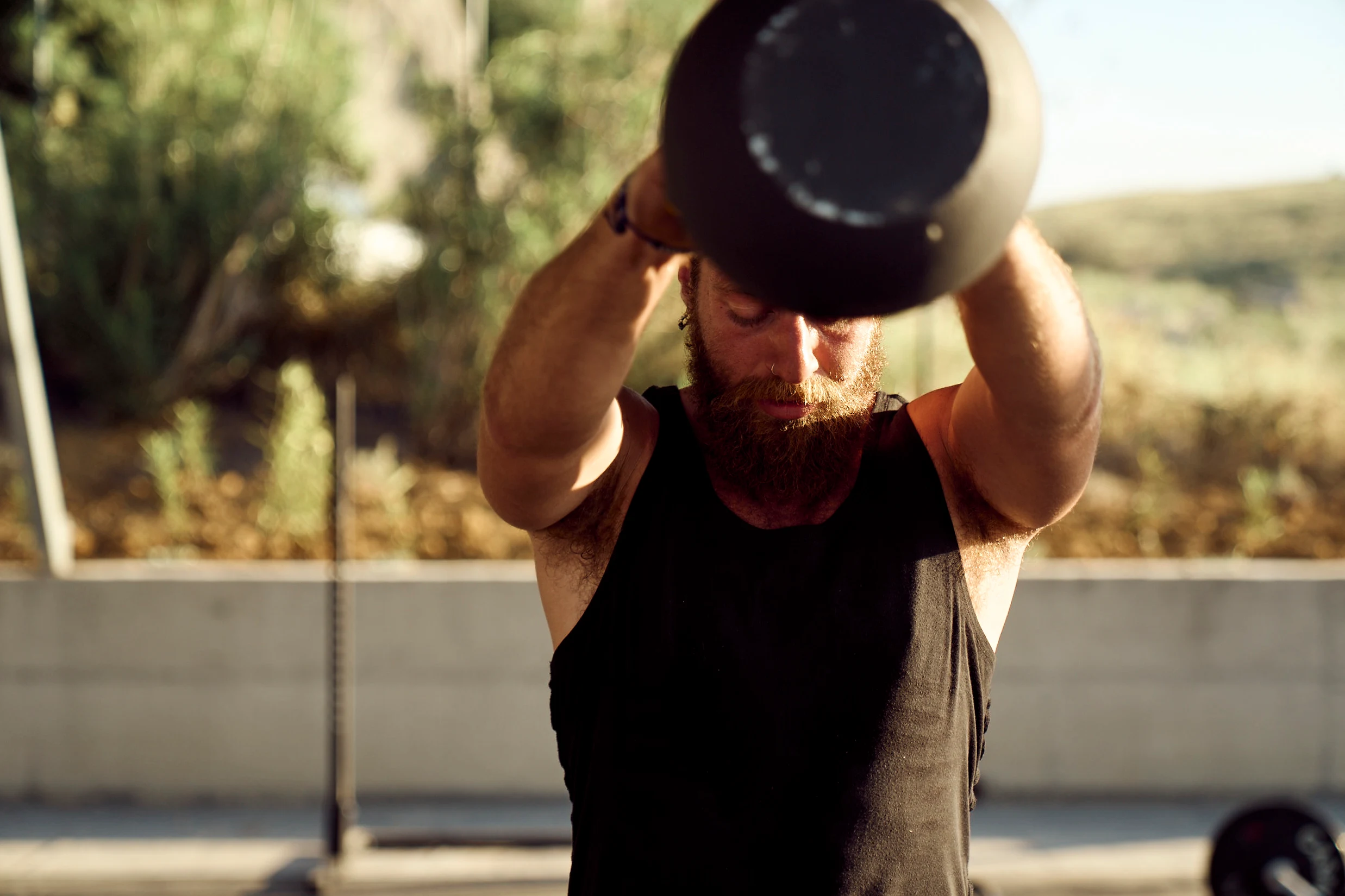 Een man met een baard doet een kettlebell-swing