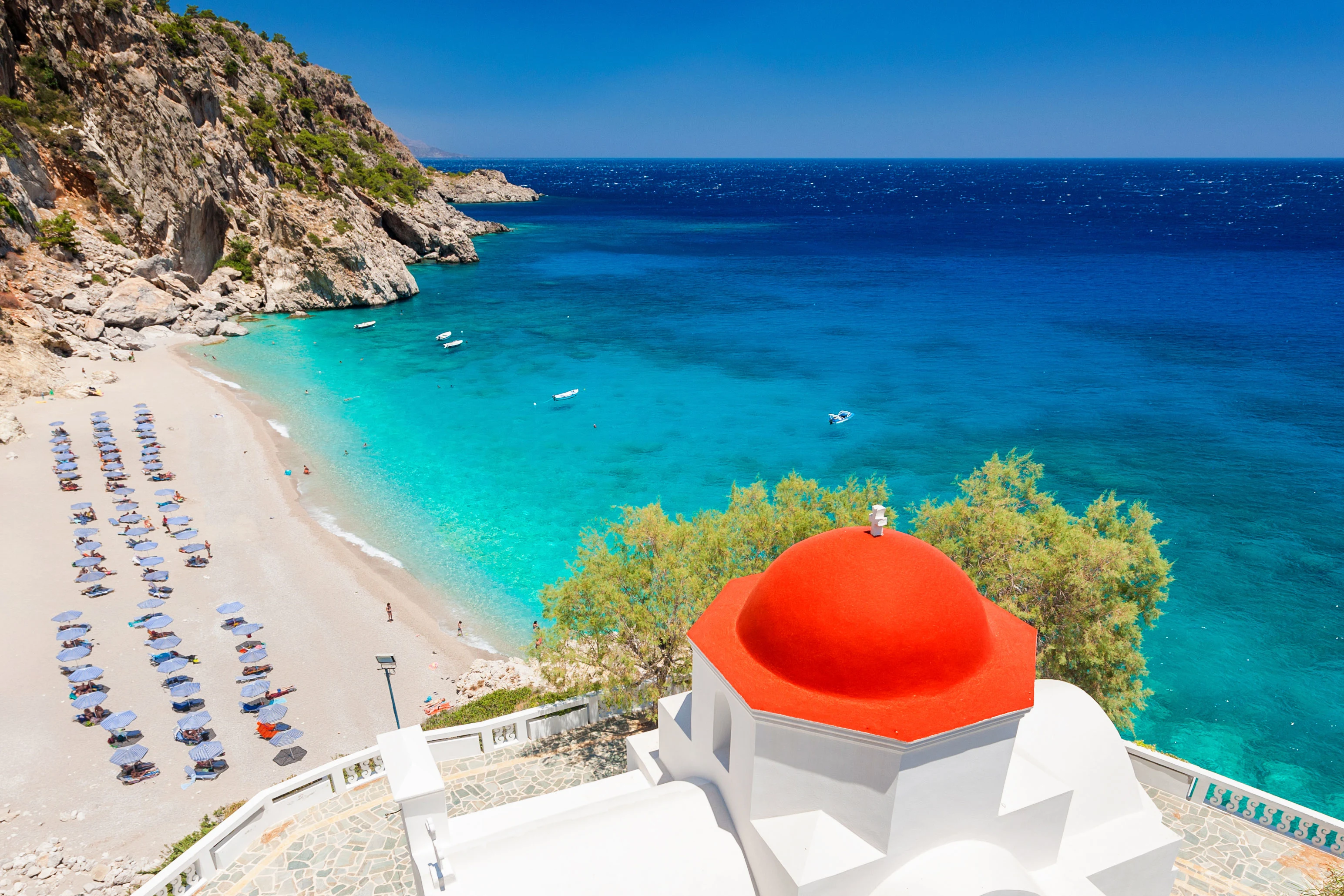 Stranden Kyra Panagia på Karpathos med en kyrka med rött tak i förgrunden