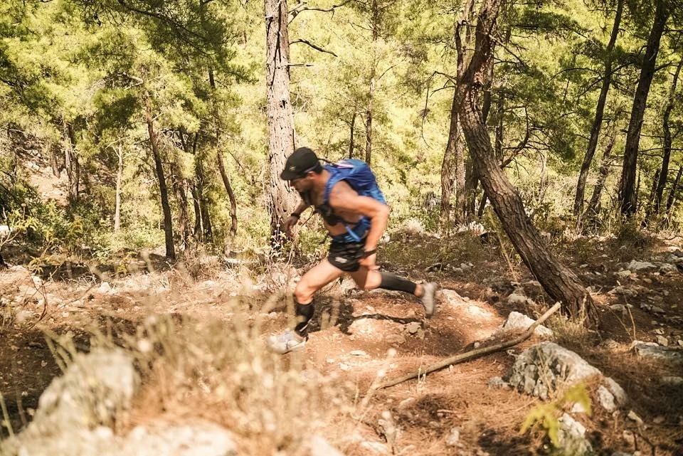 En person som løper opp en skogssti med trær i bakgrunnen på en solskinnsdag.