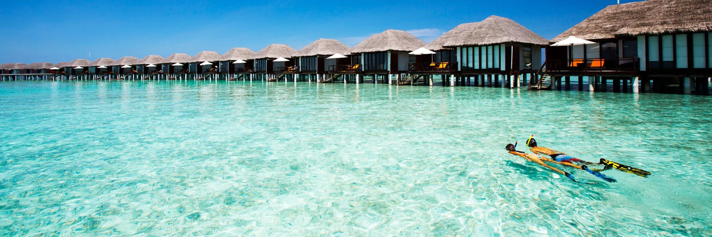 Et par som snorkler utenfor bungalower på Maldivene