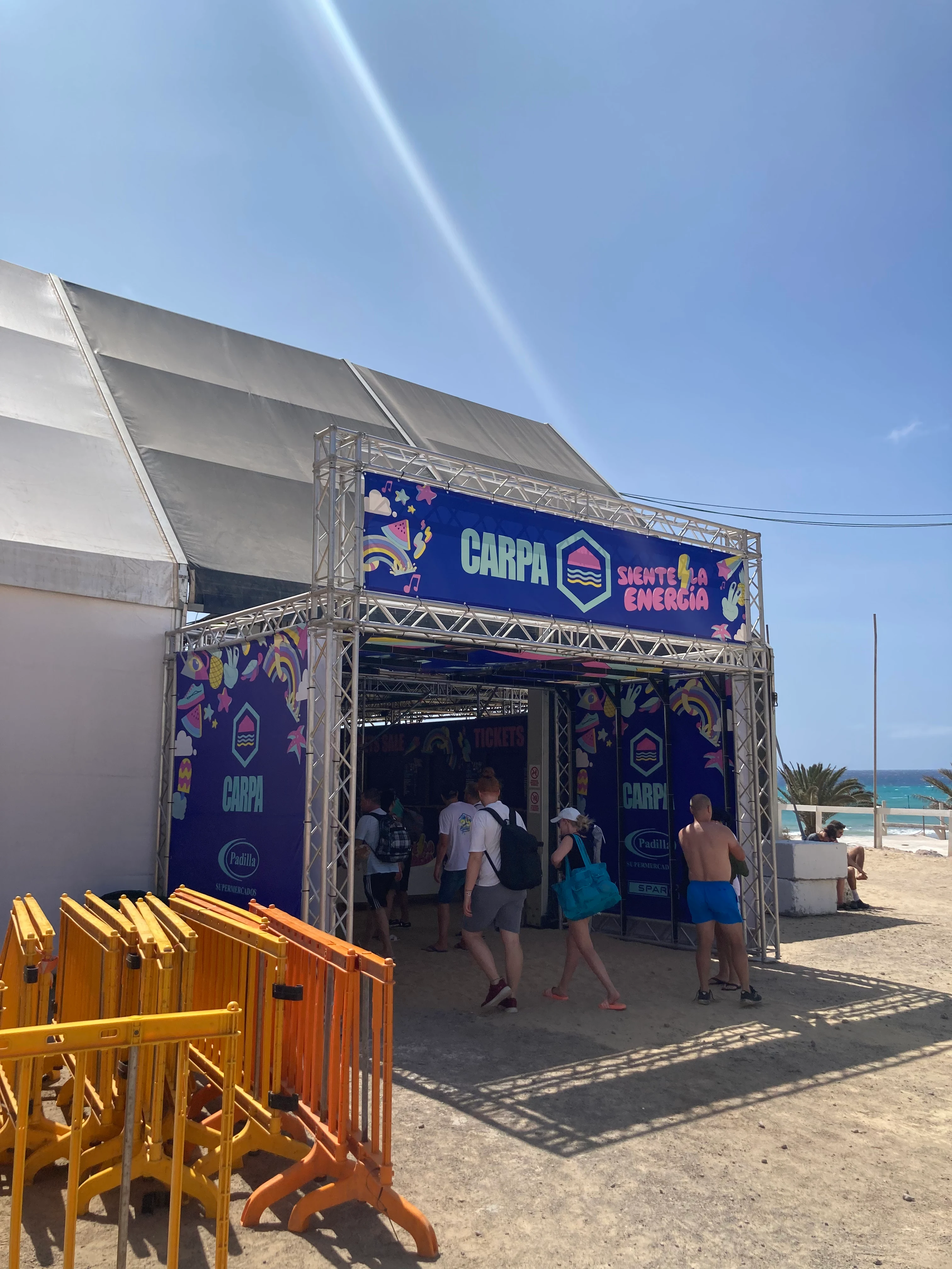 Inngang til et festivaltelt på stranden med Carpa-skilt og festivaldeltakere