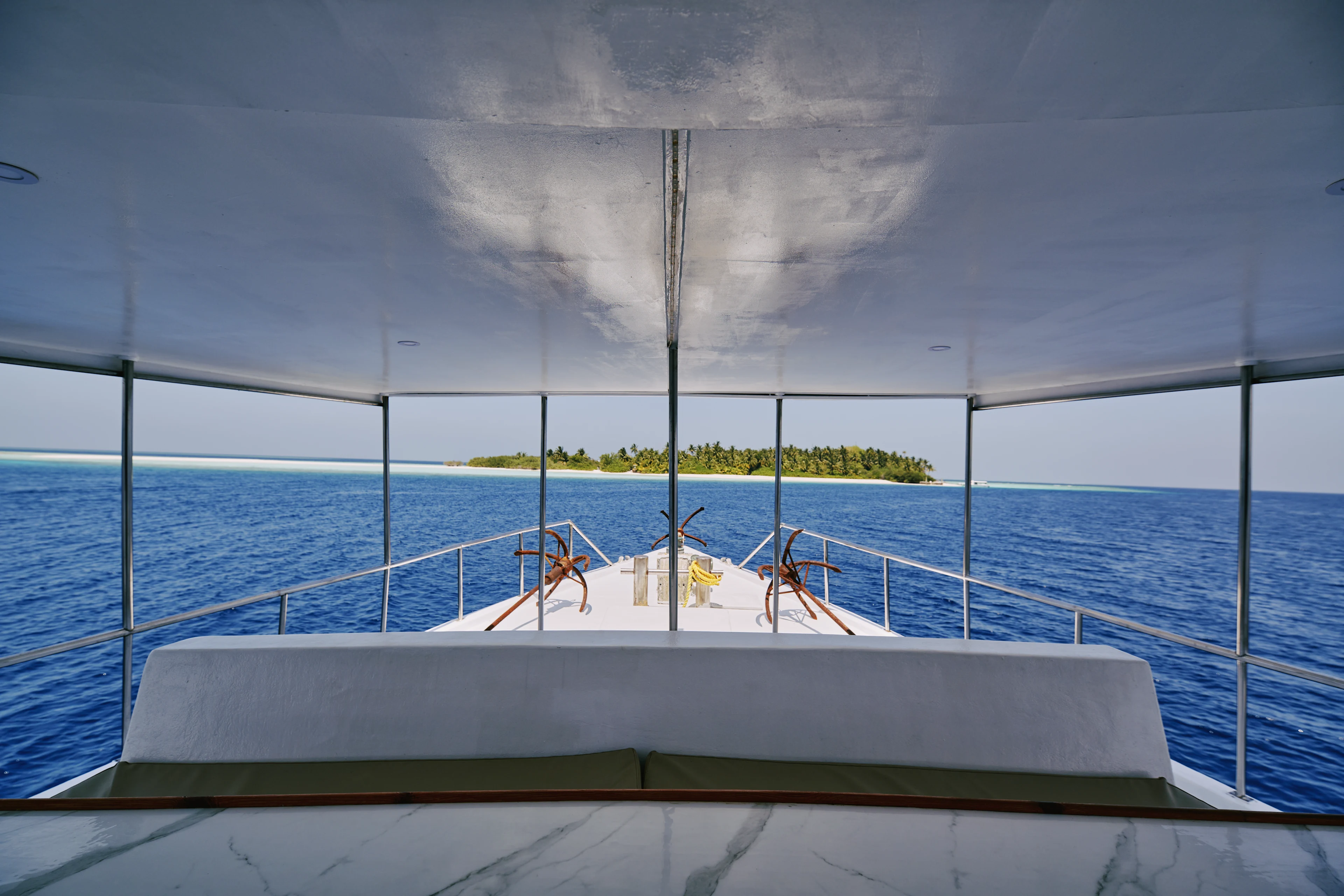 Udsigt fra en båd over et klart blåt hav mod en lille, grøn ø i det fjerne