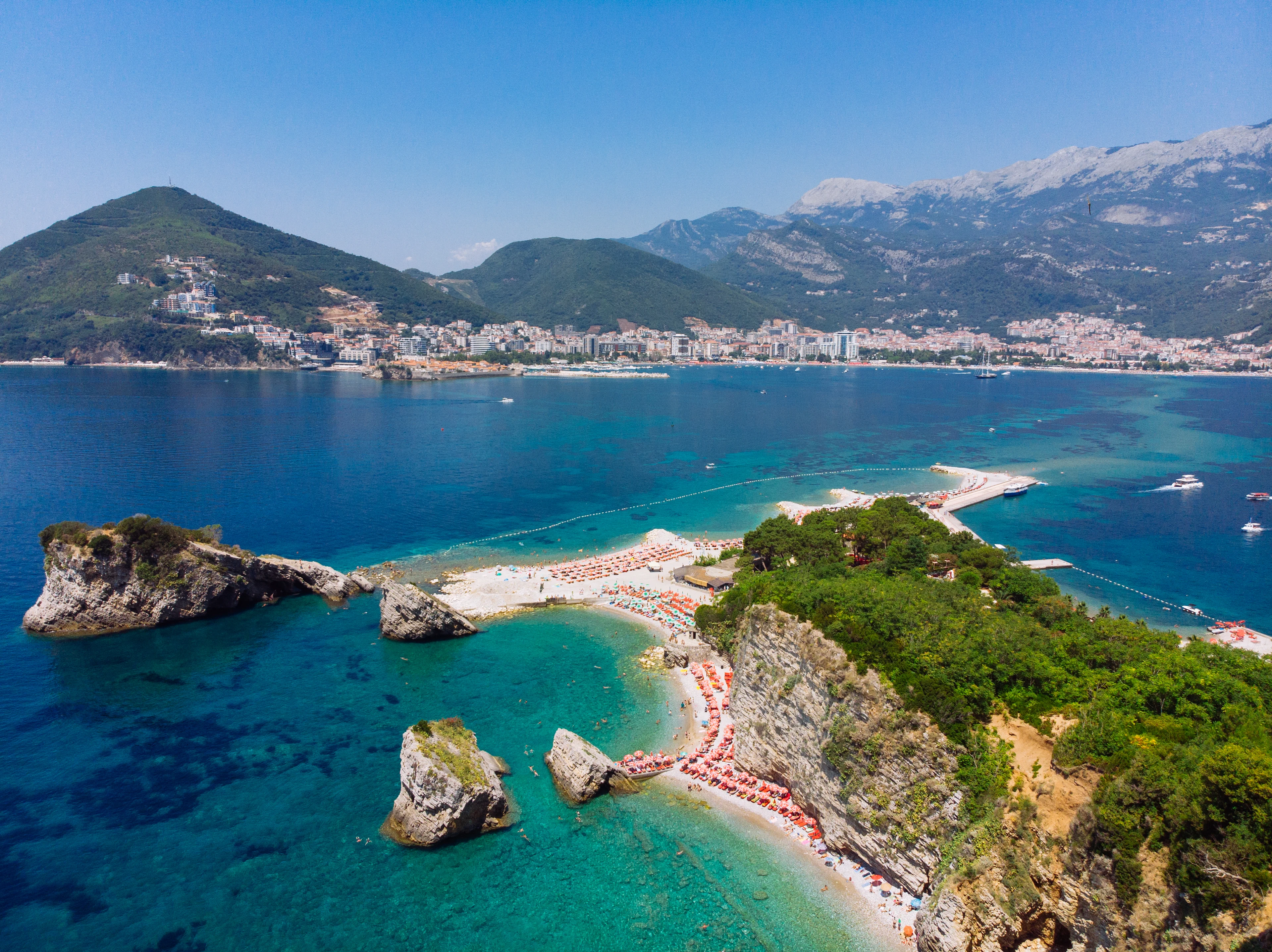 Flygfoto över stranden Sveti Nikola med kristallklart vatten och omgivningar med grönklädda berg i Montenegro