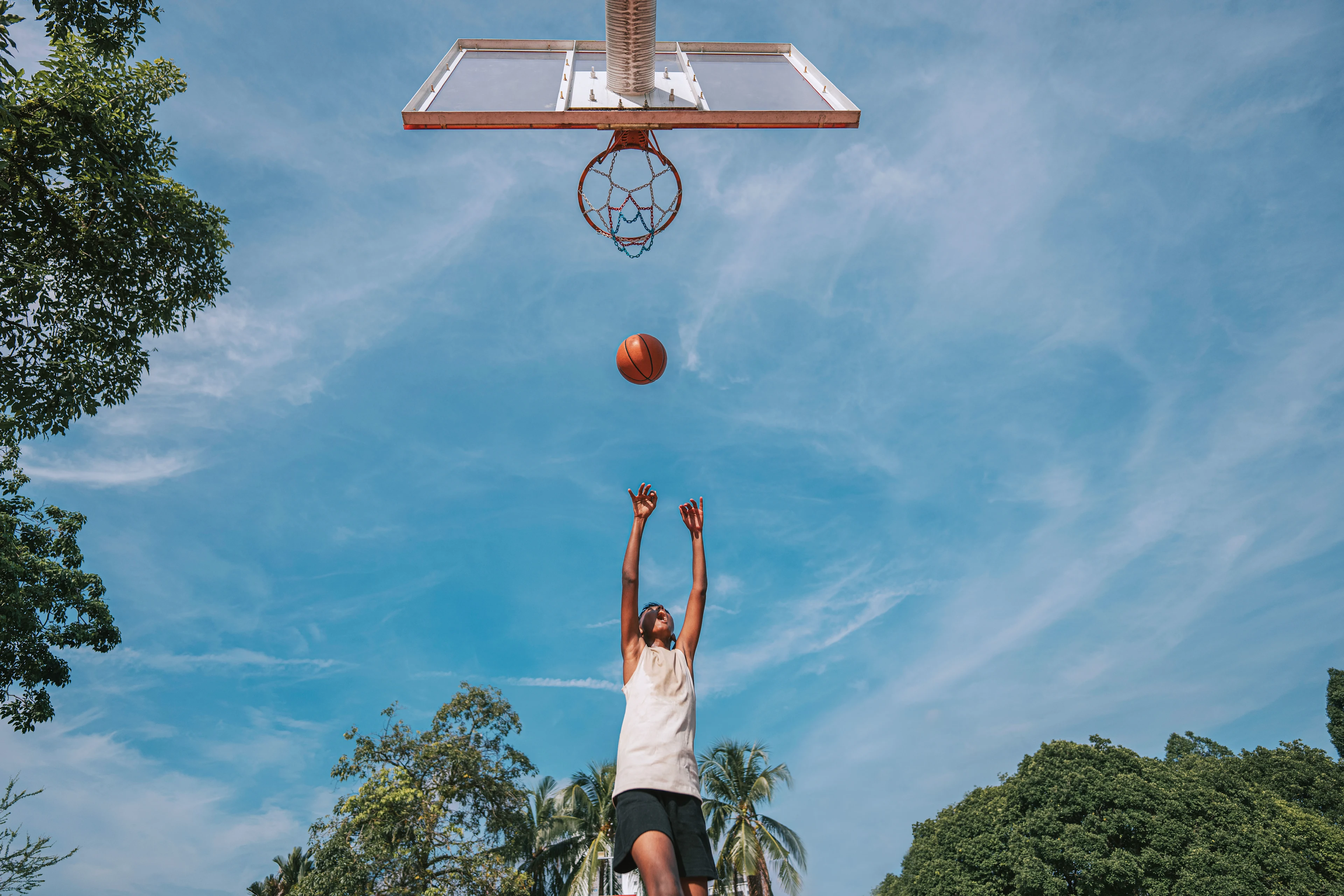 Tonåring som spelar basket och är på väg att sätta bollen i korgen