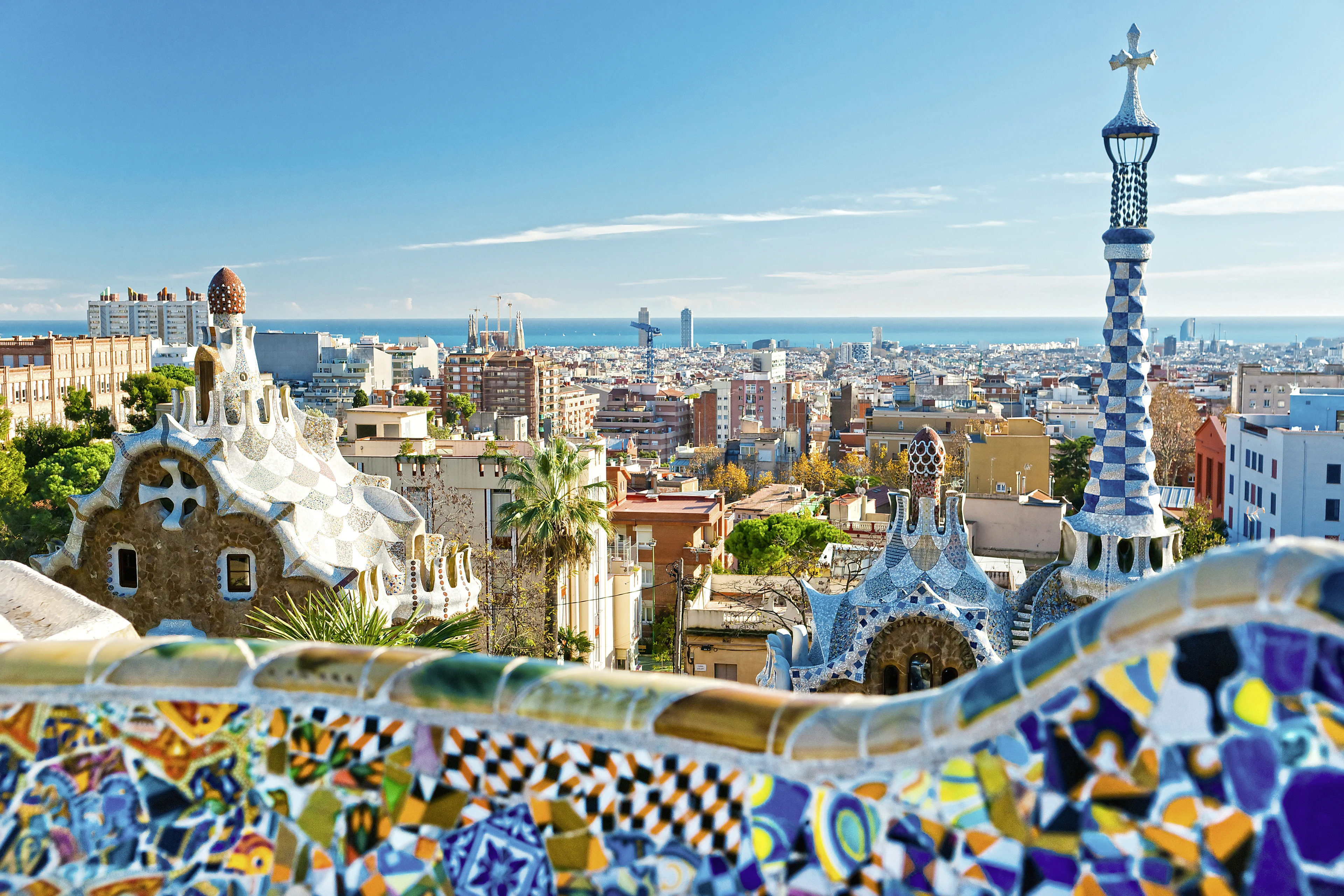 utiskt över Barcelona stad med byggnader från Parc Güell med mosaik i förgrunden och havet i horisonten 