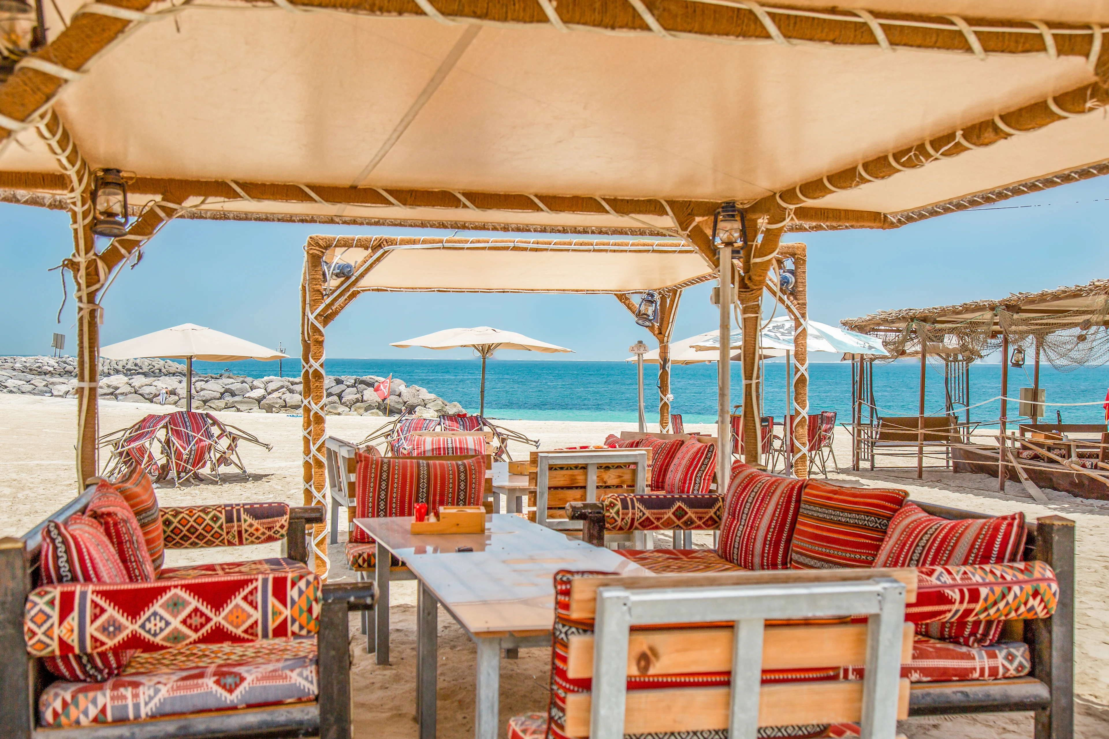 Strandrestaurang med öppna sittplatser, tropisk strand med parasoller.