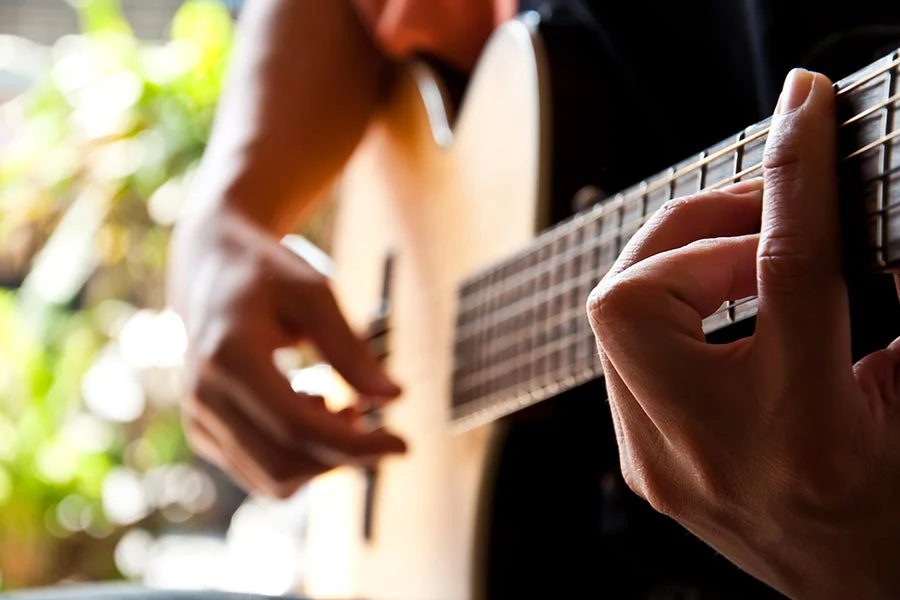 Närbild på händer som spelar på en gitarr