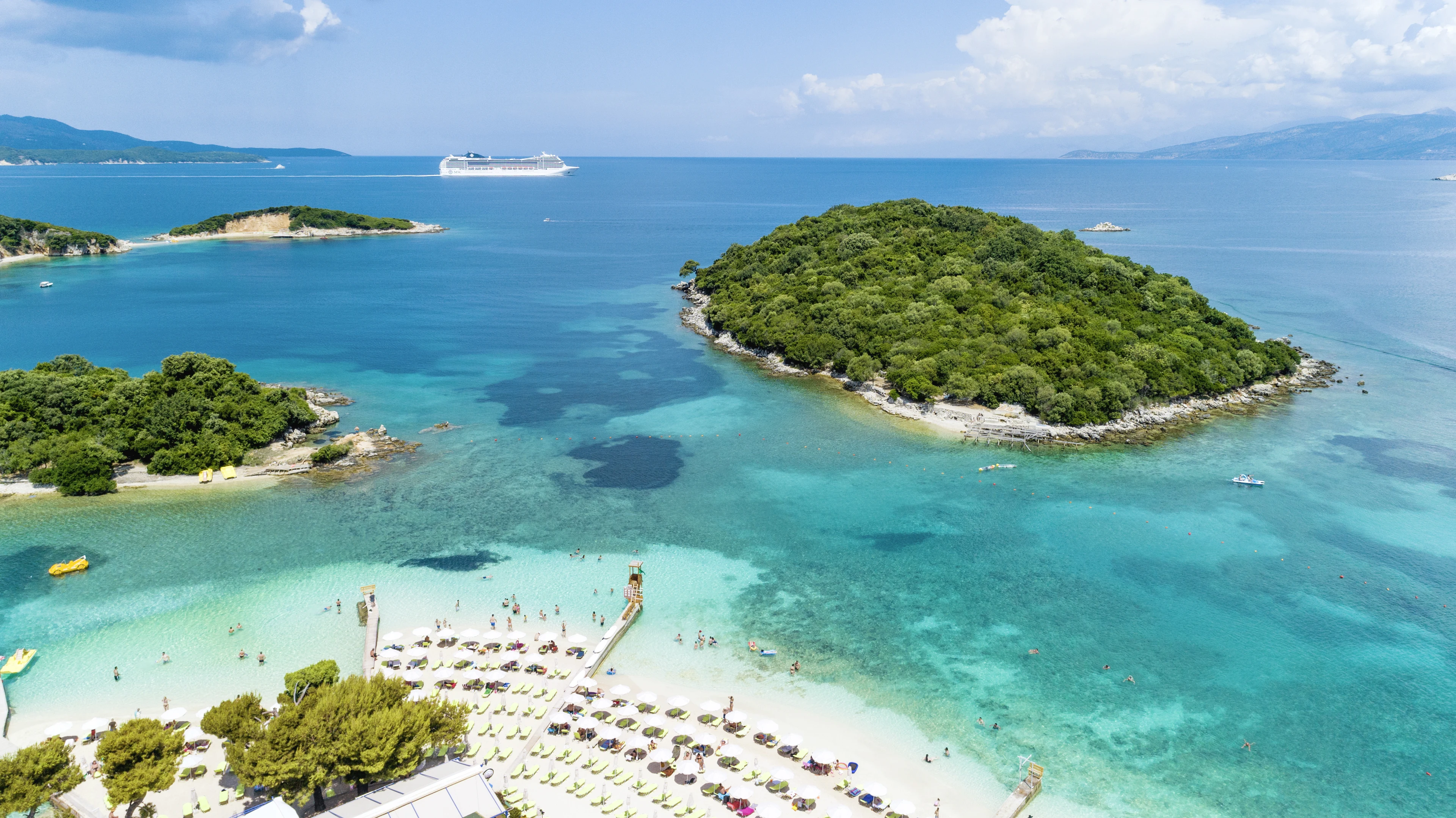 strand i ksamil med solstolar och parasol med små öar ute till havs