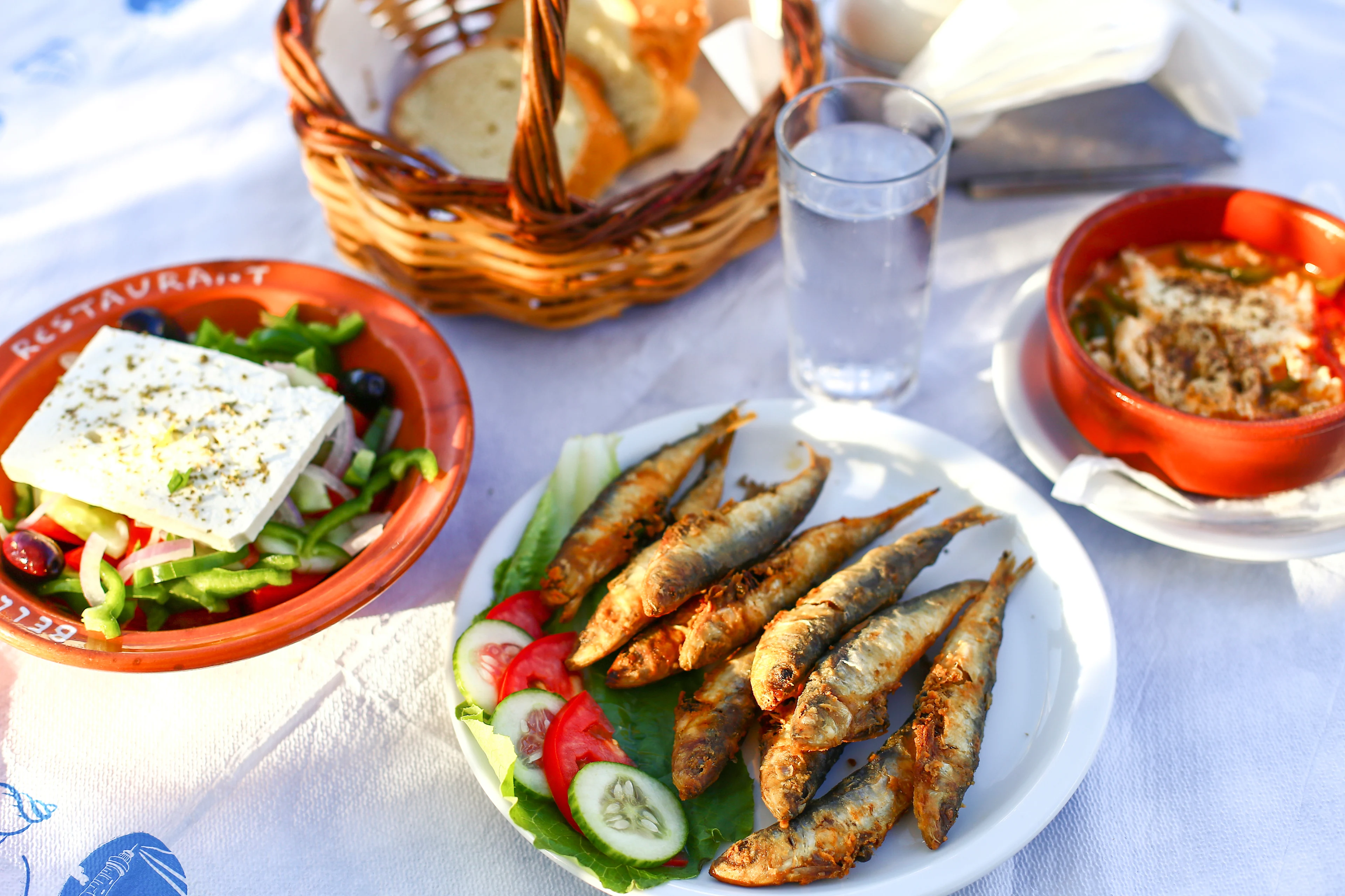 Et gresk måltid med grillede sardiner, salat med fetaost og ouzo på bordet ved sjøen