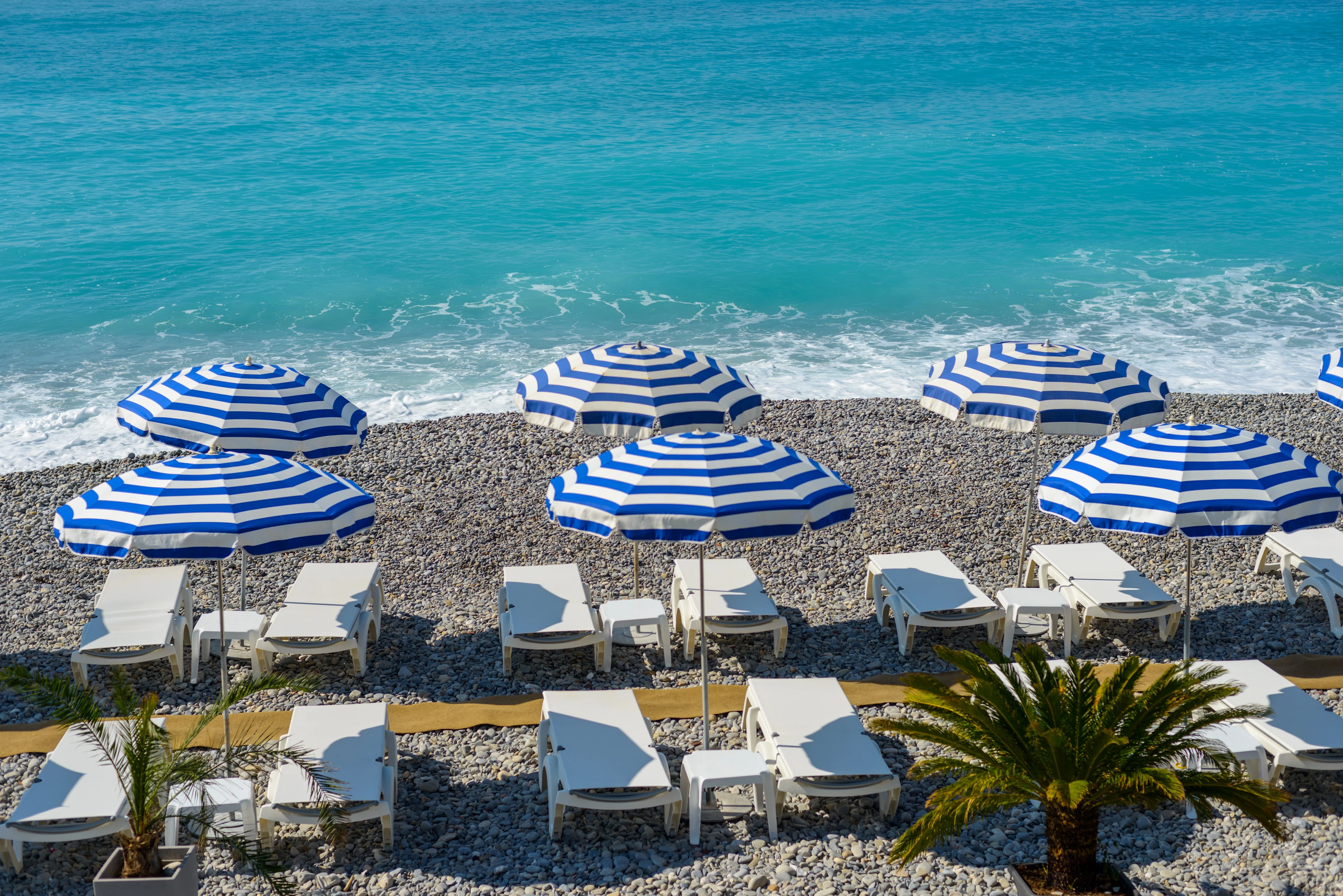 Blå och vita parasoller på stranden i Nice