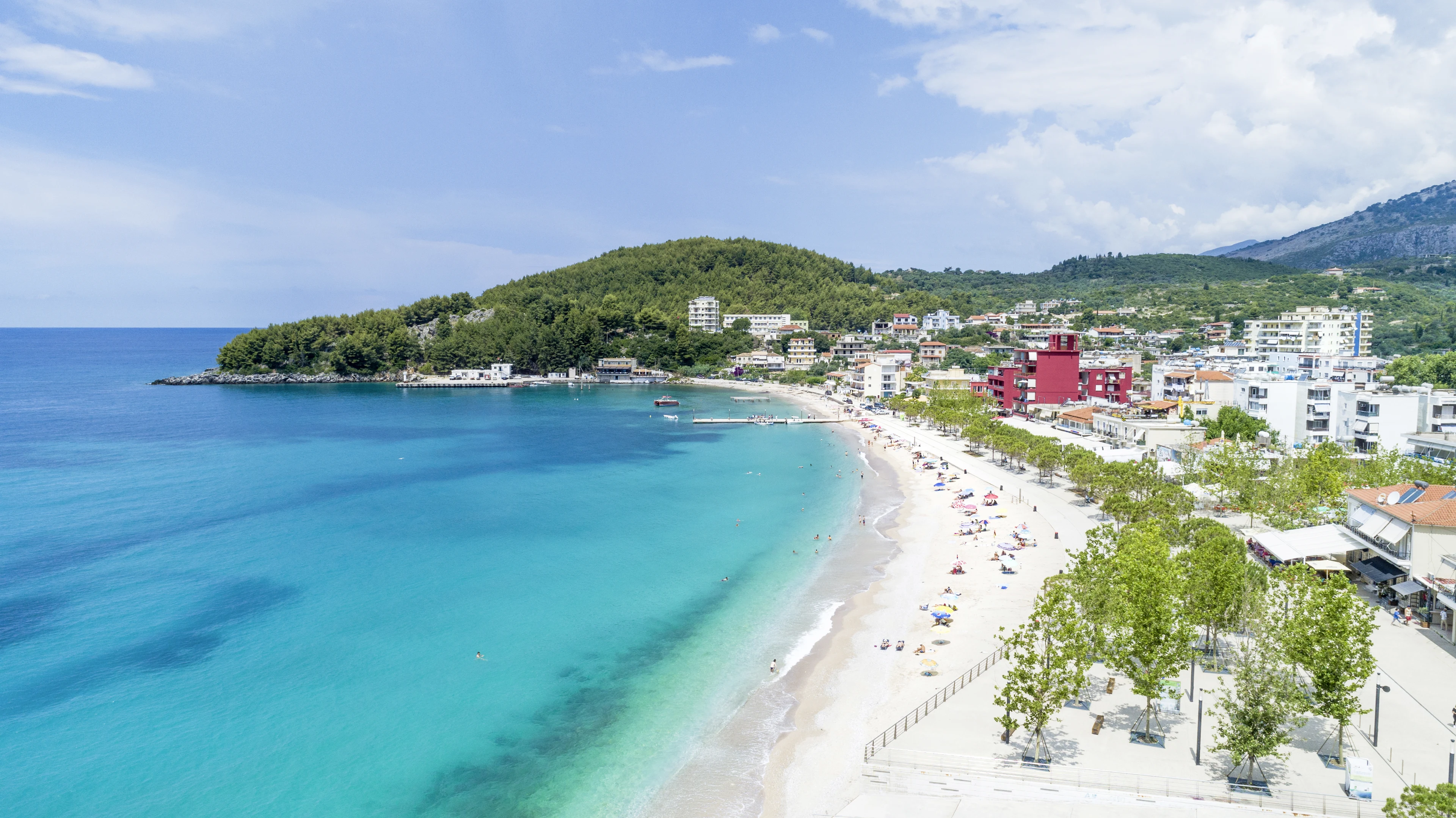 strand i Himara med utsikt över staden och bergen i bakgrunden