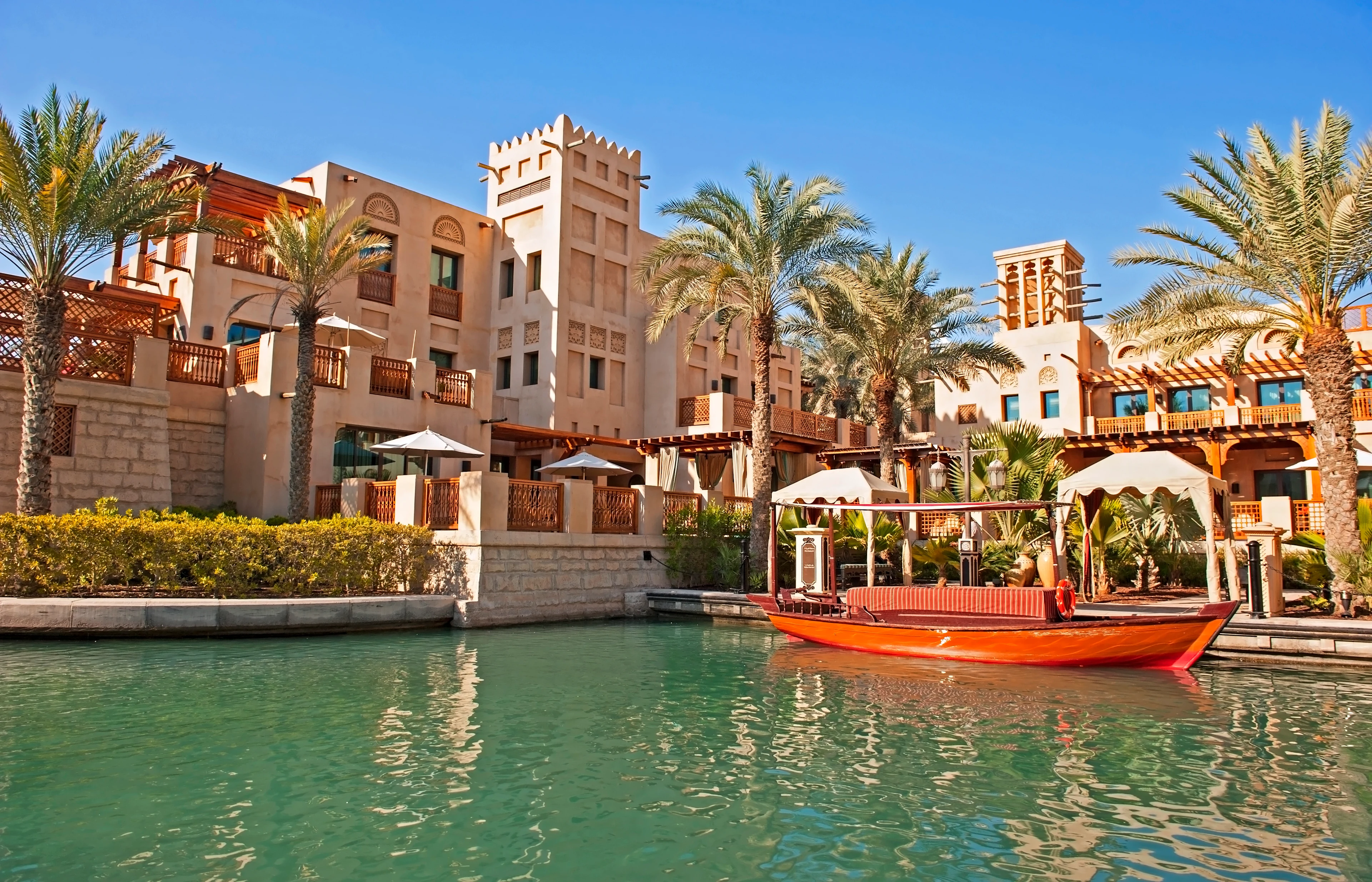 Souk Madinat Jumeirah i Dubai med traditionell abra på kanalen och arabiskinspirerad arkitektur omgiven av palmer