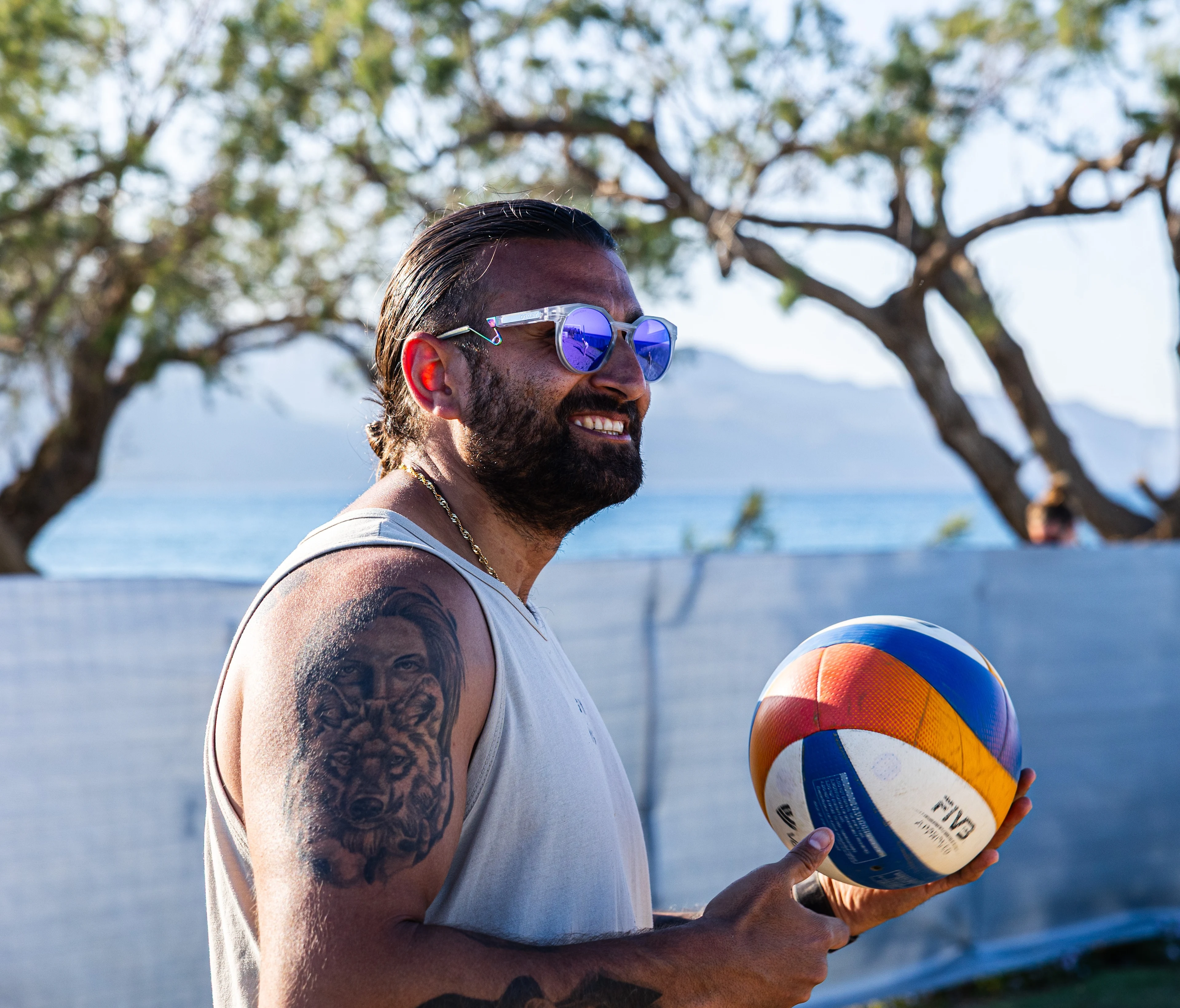 Profilbilde av Puya Sultani ikledd en hvit singel og solbriller som holder en volleyball i hendene. 