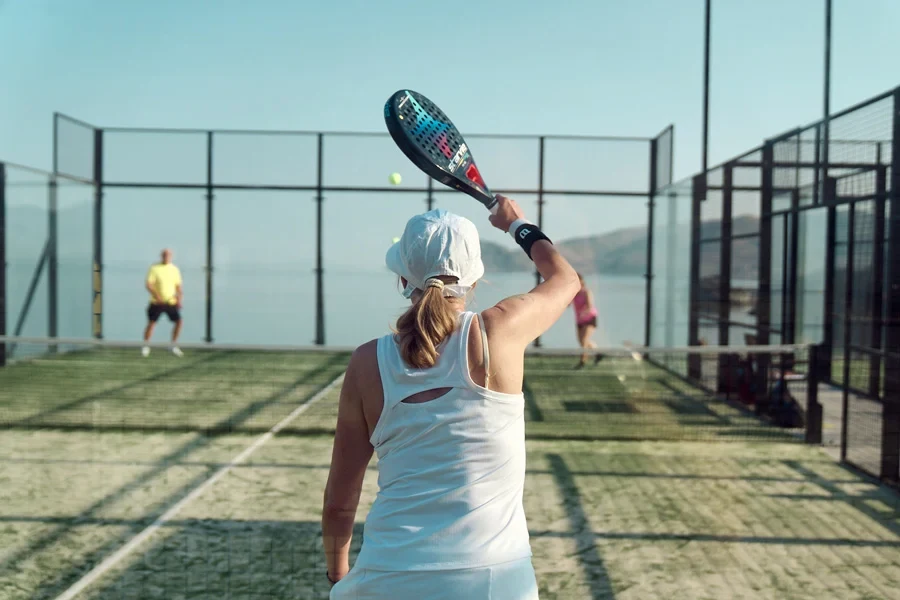 Ett par som spelar padel med hav och berg i bakgrunden 