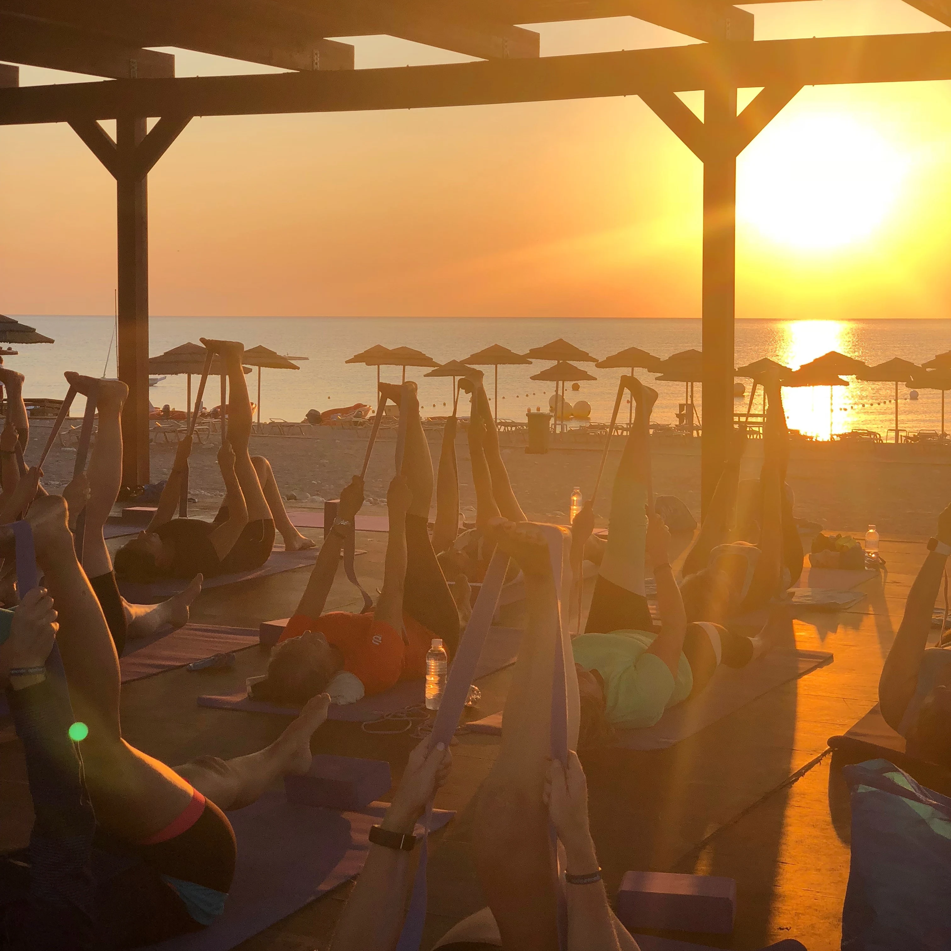 Gruppetrening i soloppgang med stranden og havet i bakgrunnen