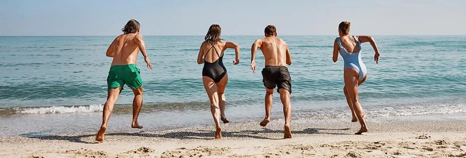 Människor springer på stranden ner mot vattnet