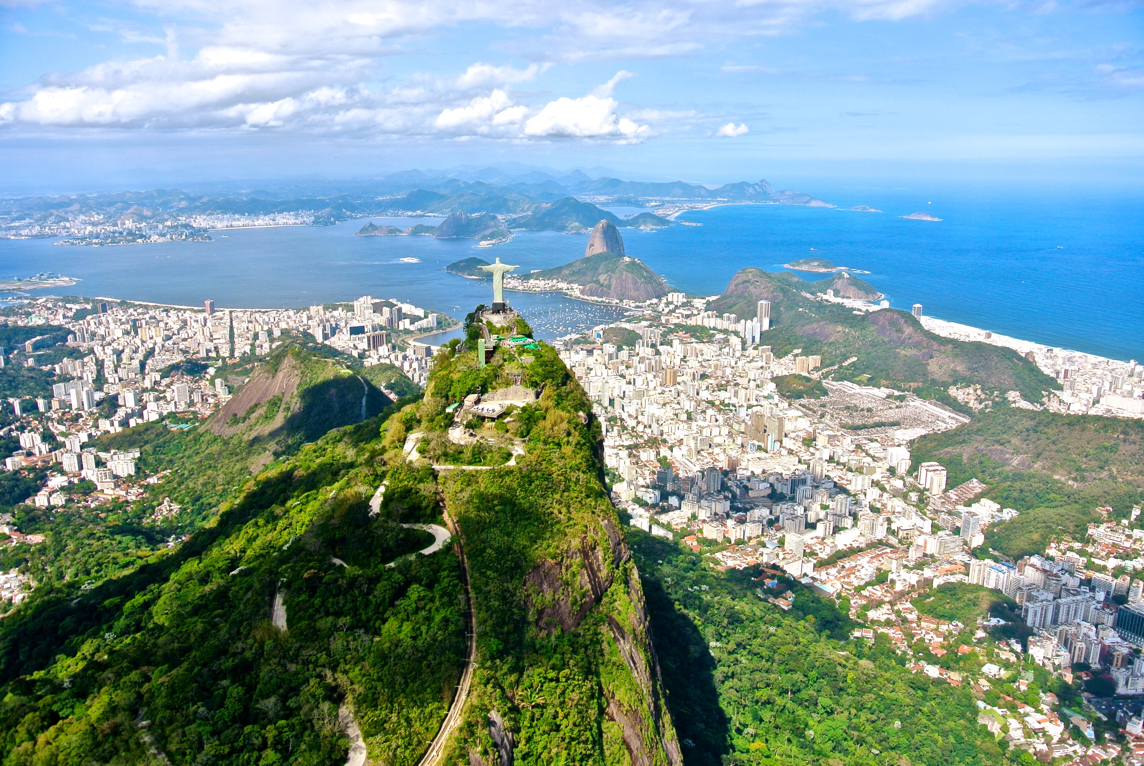 Flygfoto över Rio de Janeiro med Kristusstatyn på Corcovadoberget och stadens kustlinje i bakgrunden.