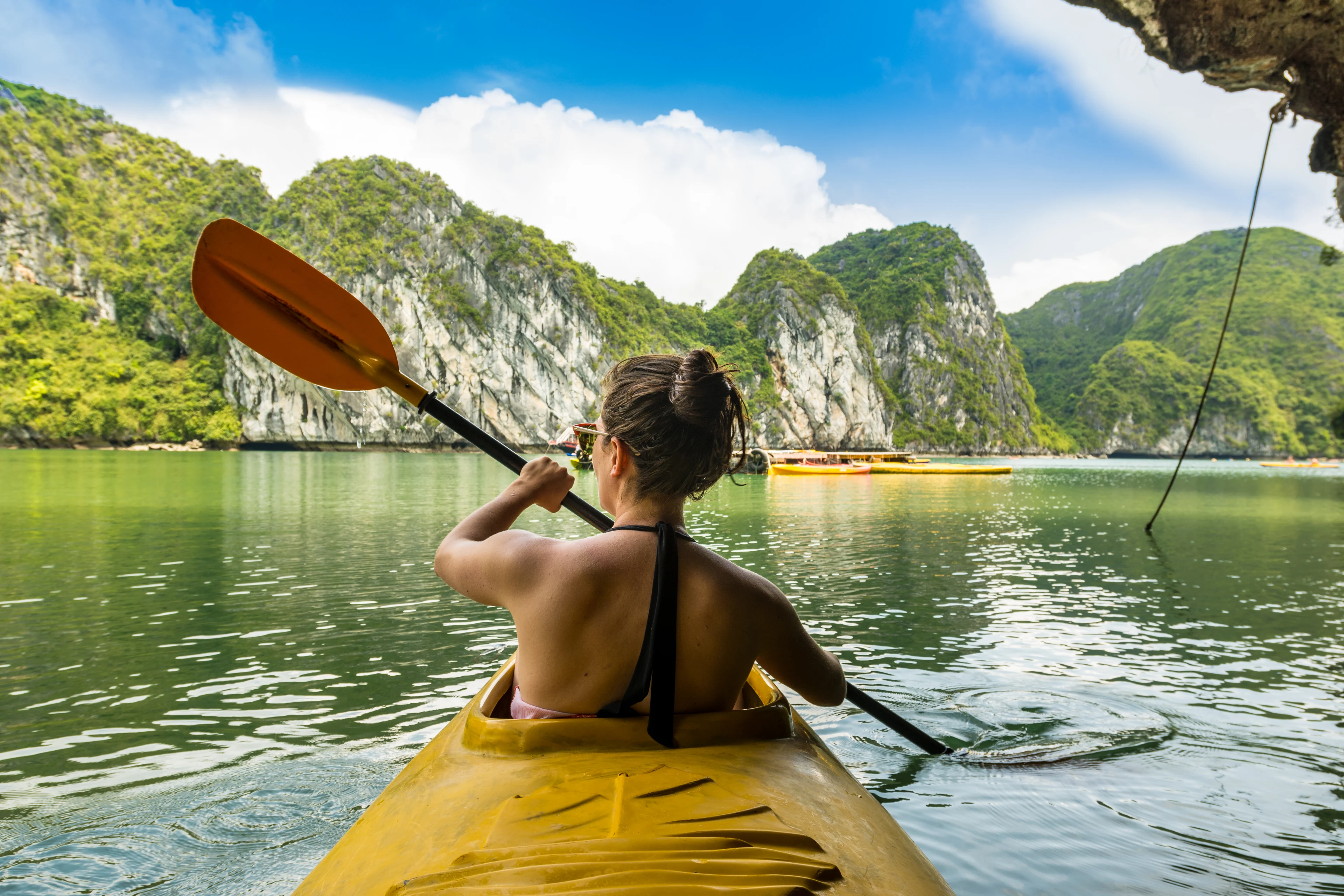 Kvinna paddlar kayak i vackra omgivningar i Halong Bay, Vietnam