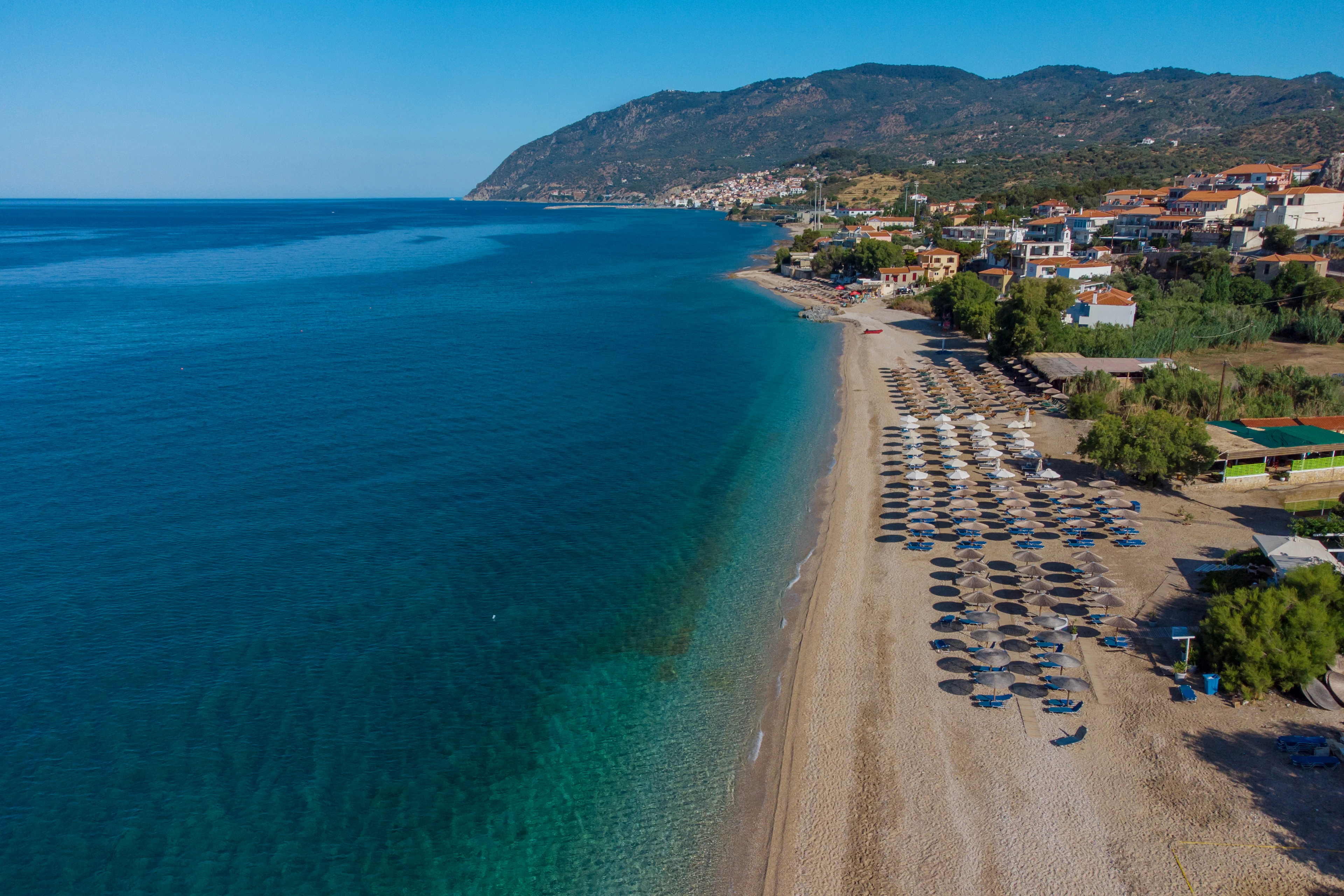 Vy över vacker strand ned solstolar och parasoll på Lesvos