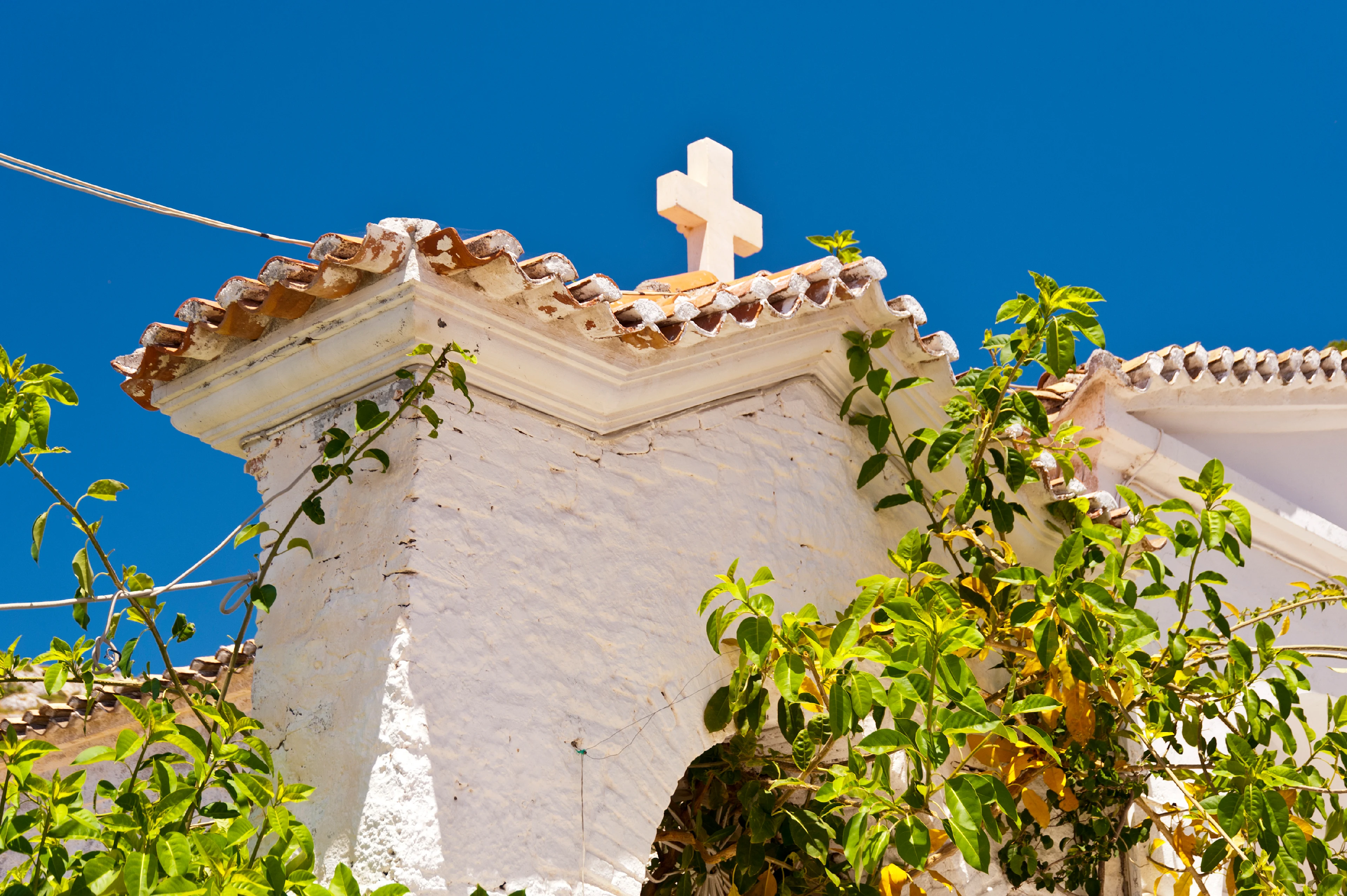 Een deel van een kerkmuur op Samos waar je een kruis op het dak kunt zien