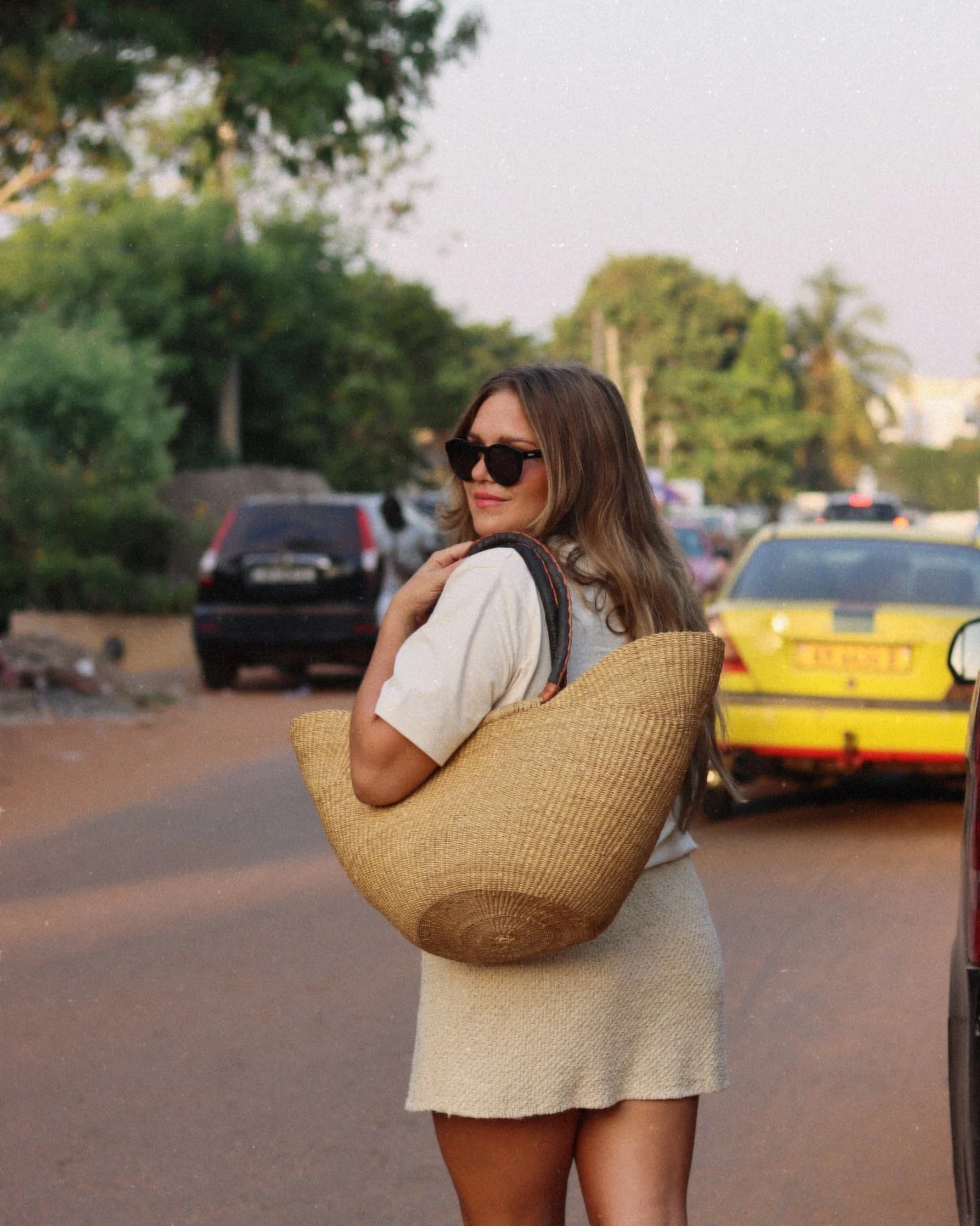 Louise håller i en strandväska och korsar en gata i Gambia