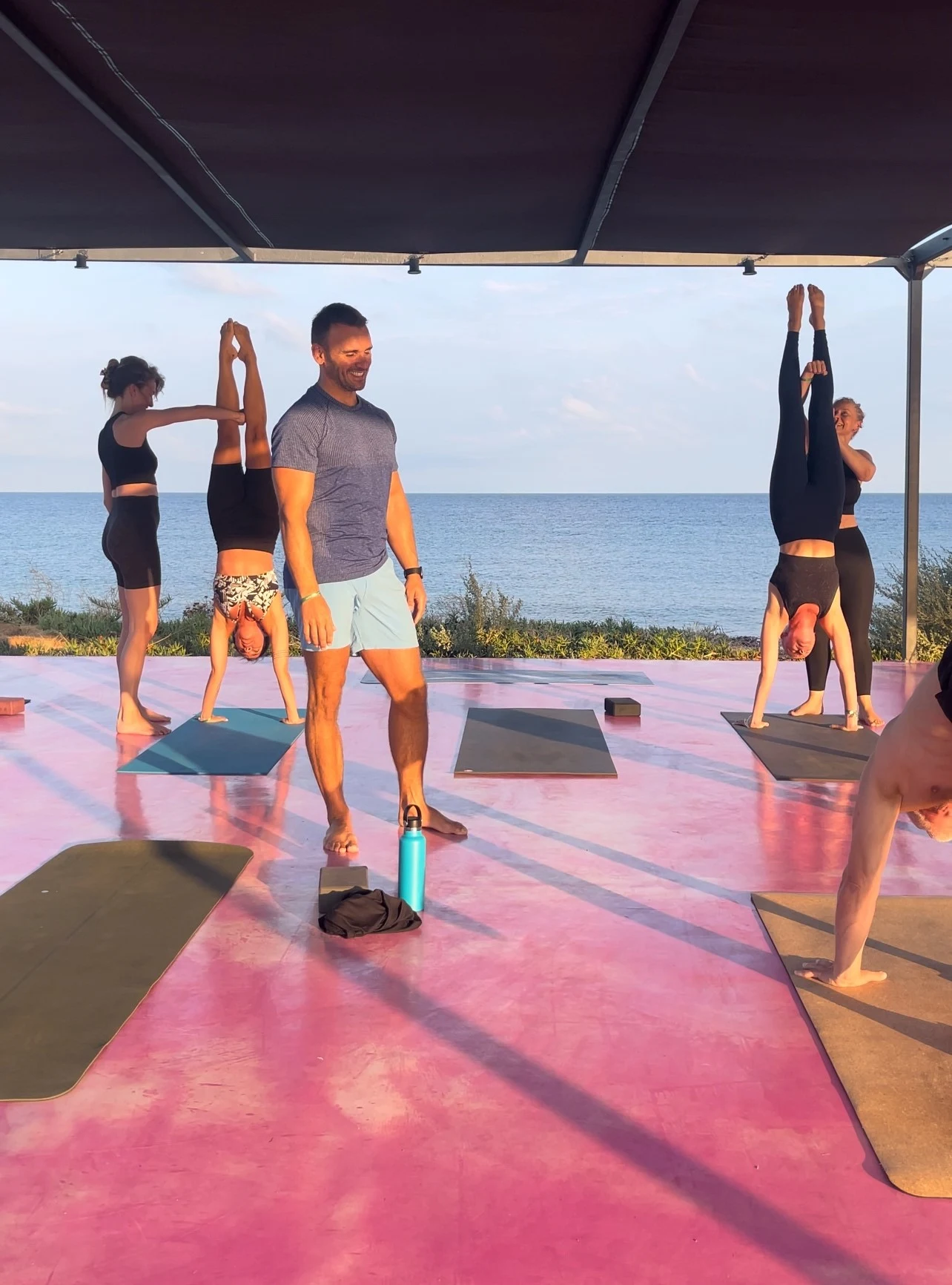 Handstand yoga på rosa plattform og instruktøren.
