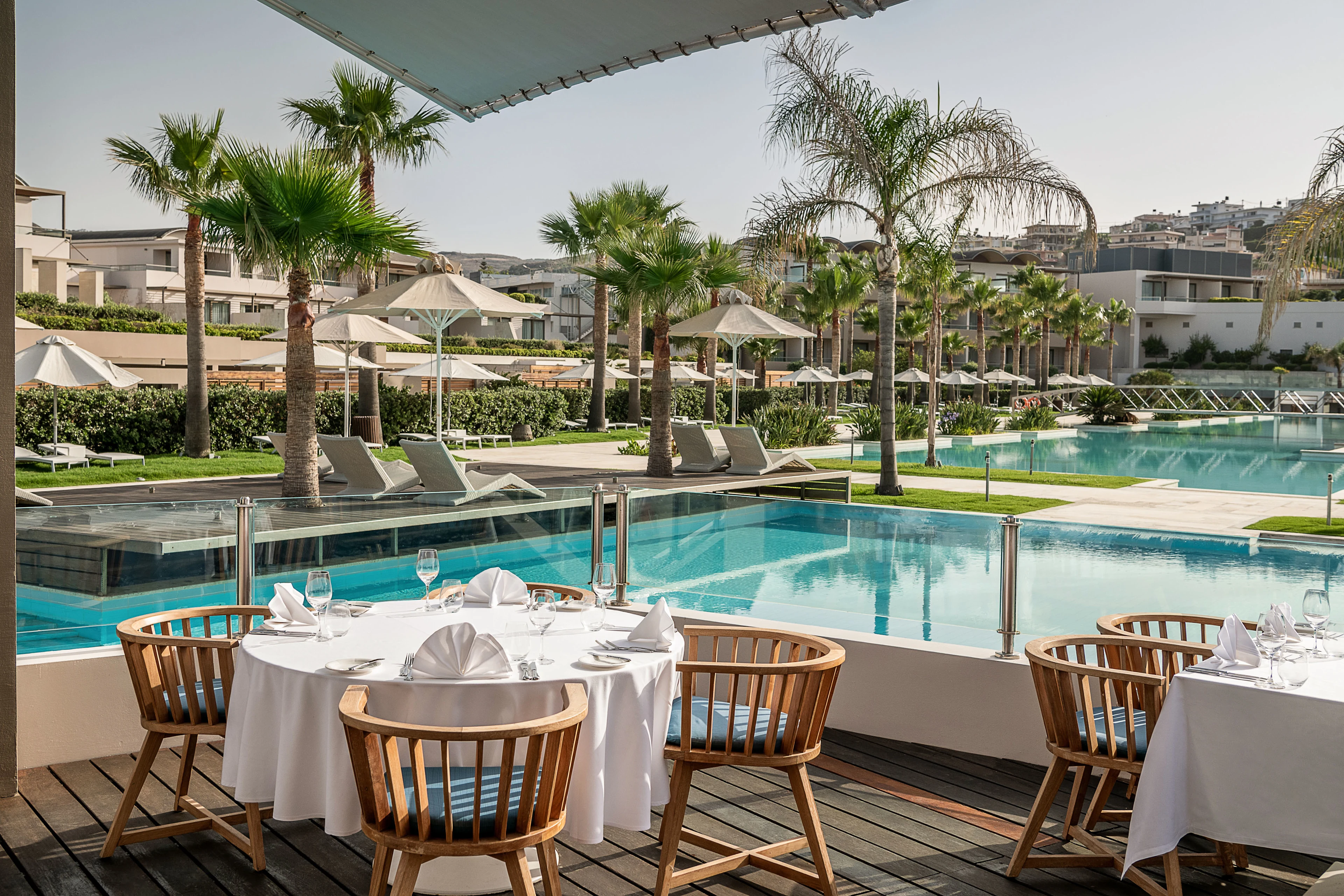 Restaurang där borden är uppdukade med vita dukar. Utsikt över poolen