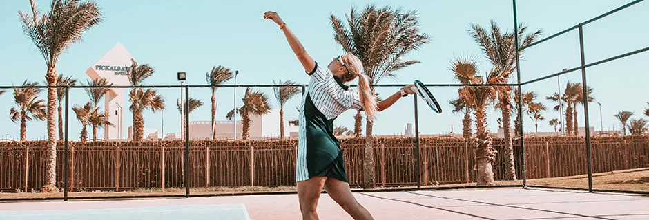 Tjej som servar på en tennisbana på Aqua Vista