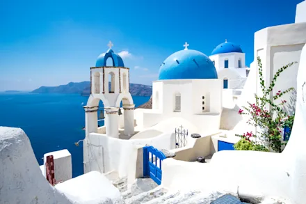 Vitkalkade byggnader med blå tak och utsikt över havet på Santorini