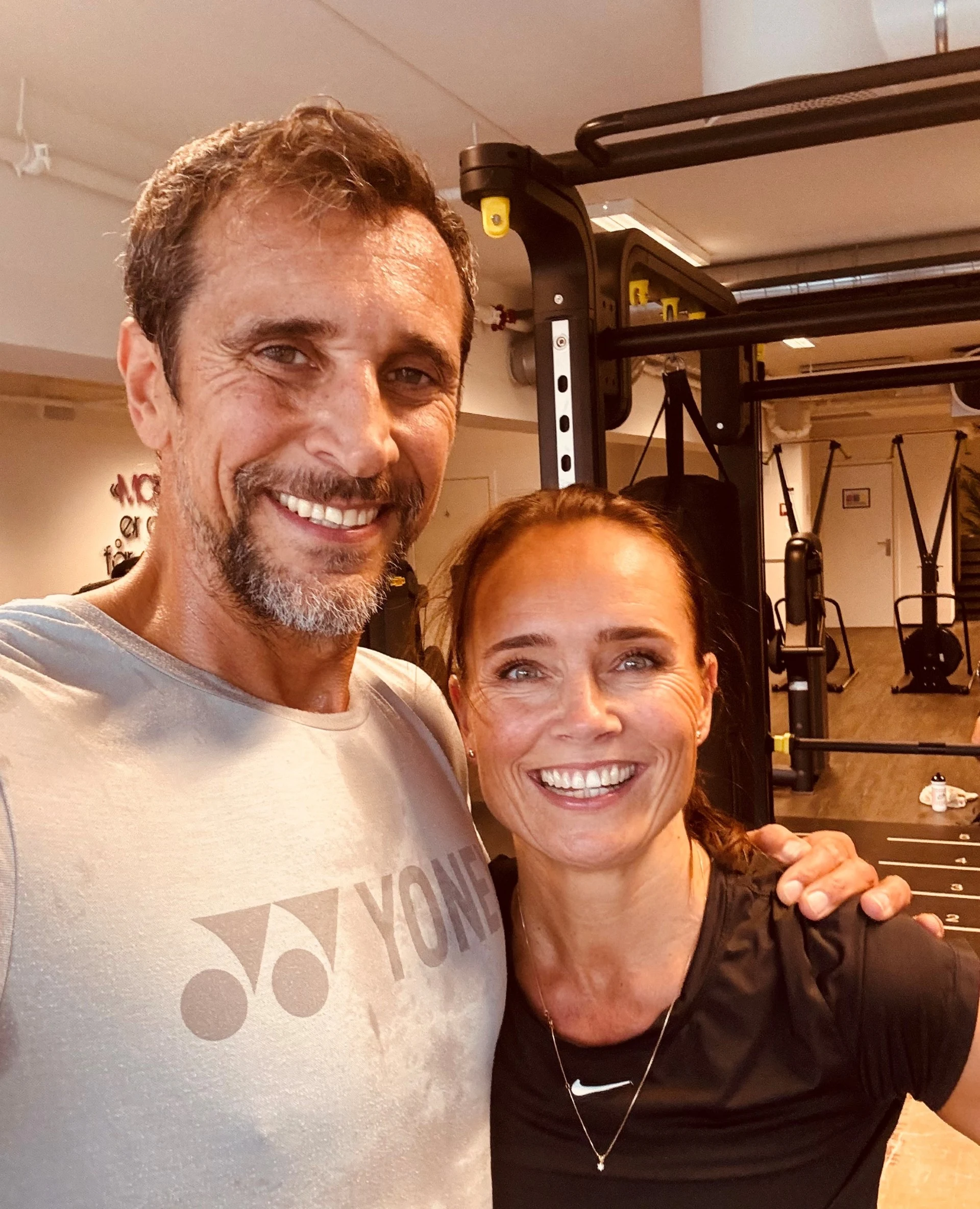Marcel og Silje står tett inntil hverandre inne på et treningssenter. 