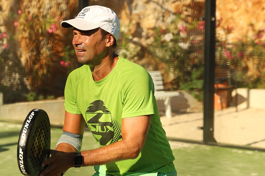 Een man staat met zijn padelracket in de hand op een padelbaan
