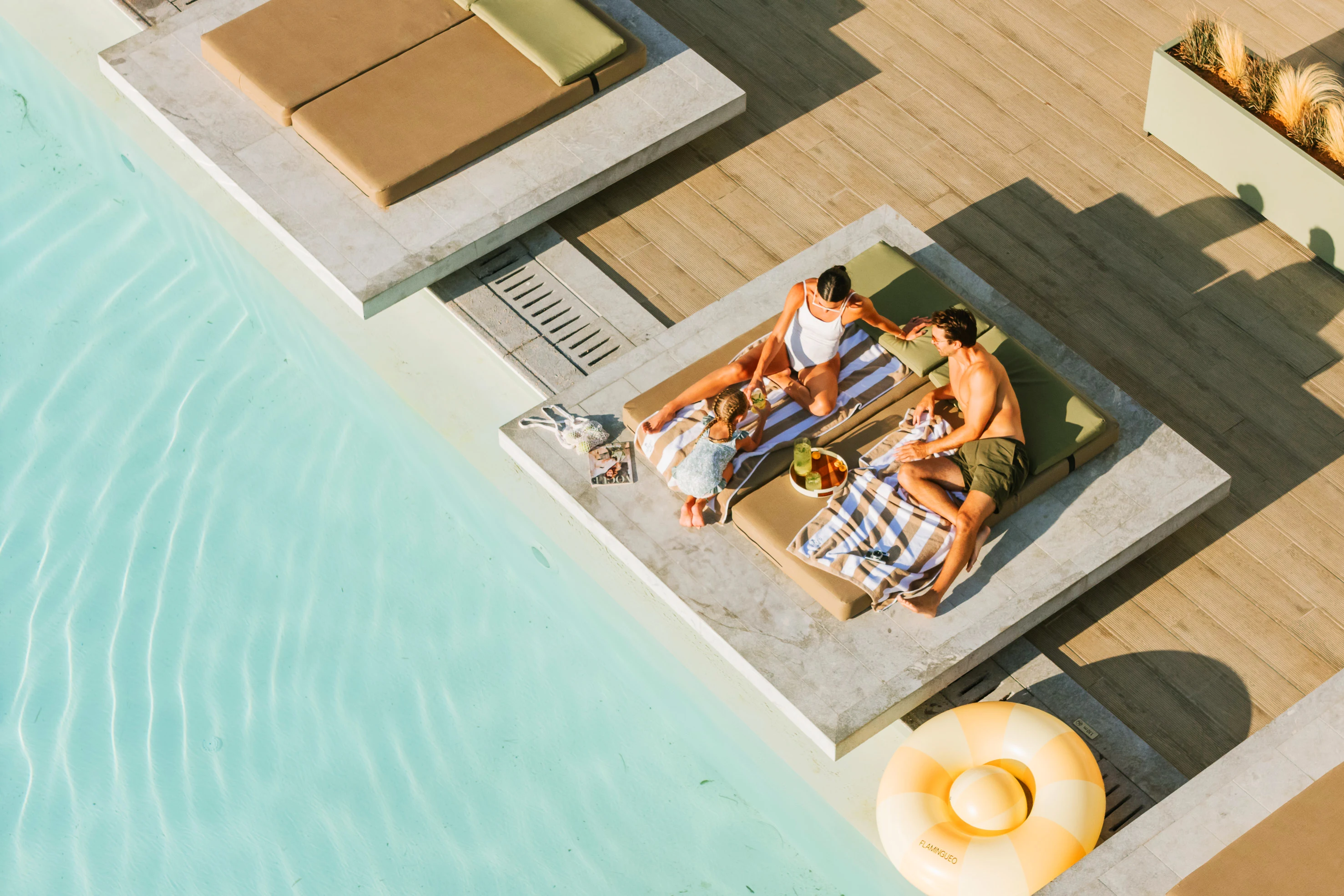 Par som ligger vid poolen på solstolar