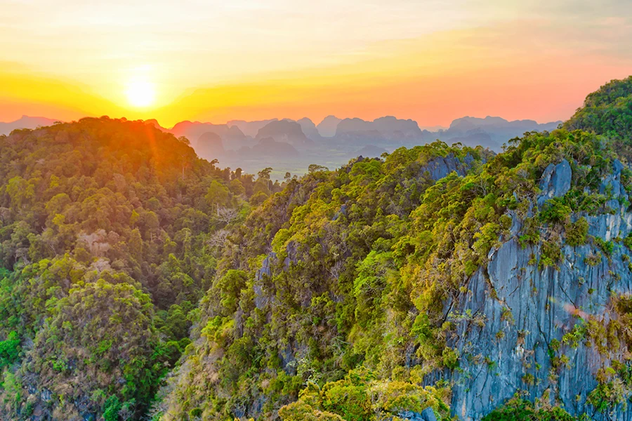 Solnedgång över Krabis grönskande kalkstensberg och tropiska landskap i södra Thailand.