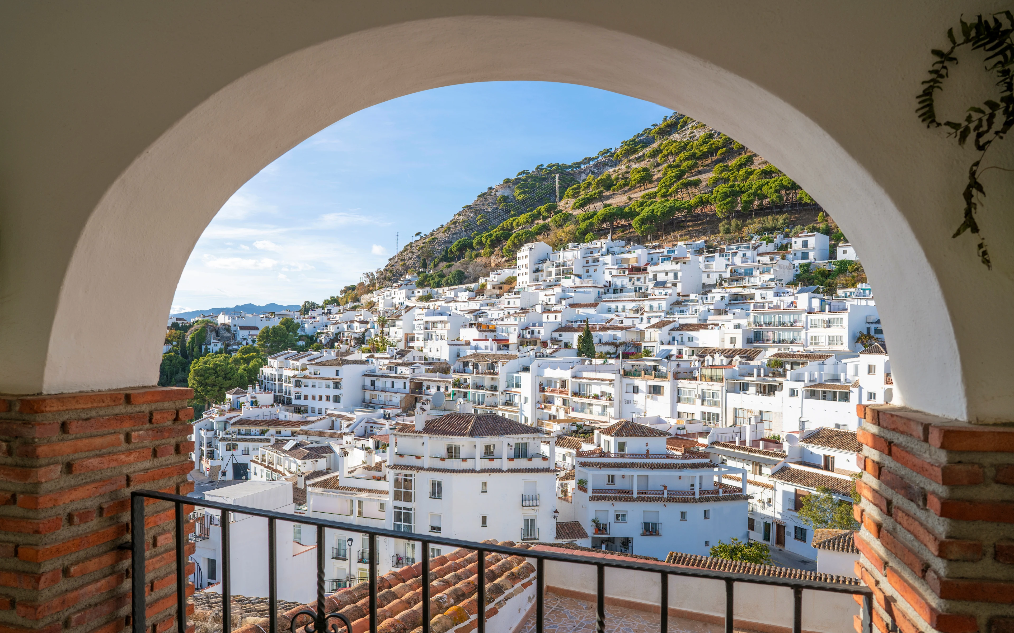 Vitkalkade hus i Mijas Pueblo med bergssluttning i bakgrunden.