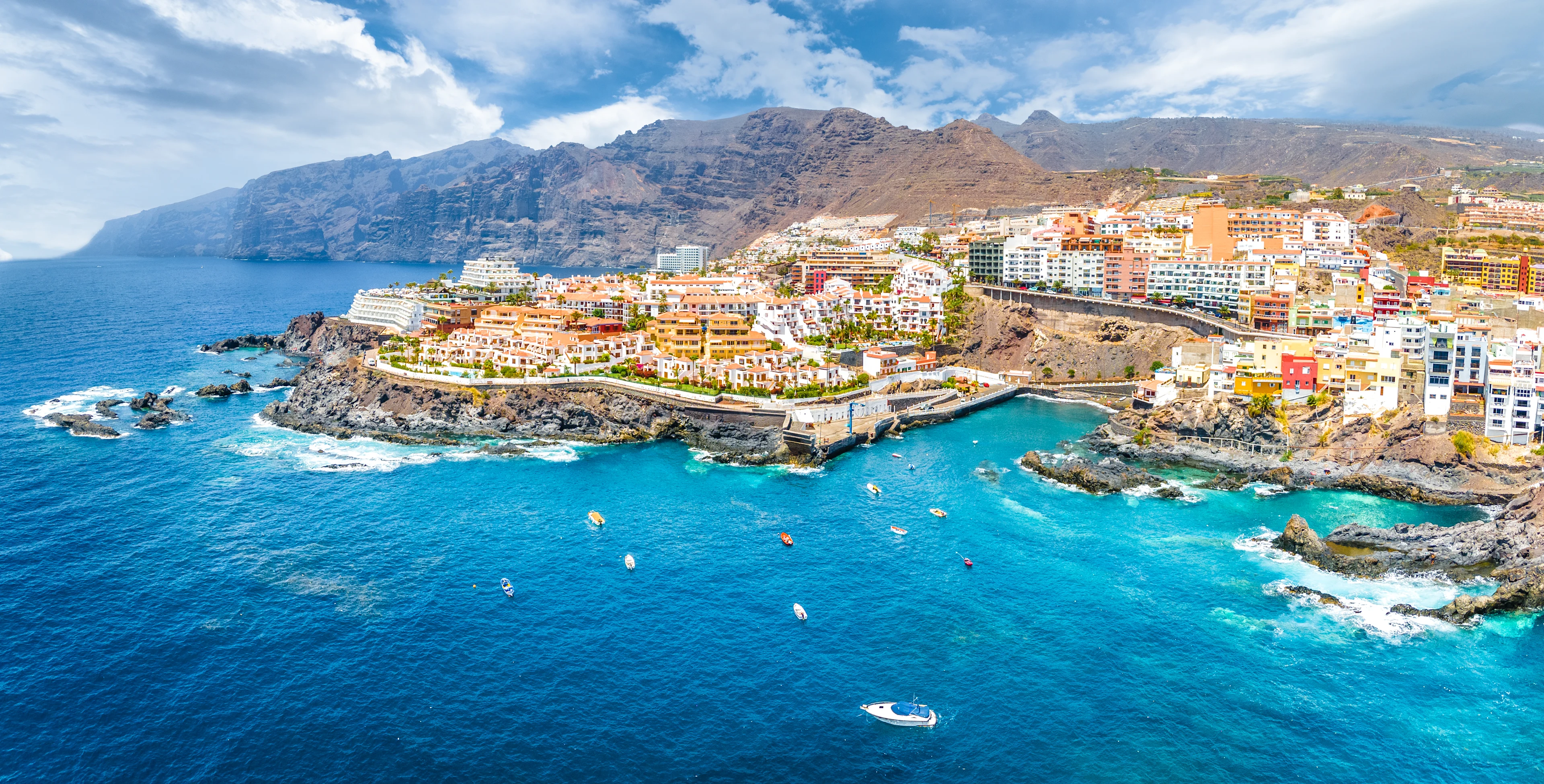 Näköala Puerto de Santiago Teneriffalla, jossa värikkäät talot kohtaavat Atlantin turkoosinsiniset vedet ja vaikuttavat Los Gigantesin kalliot.