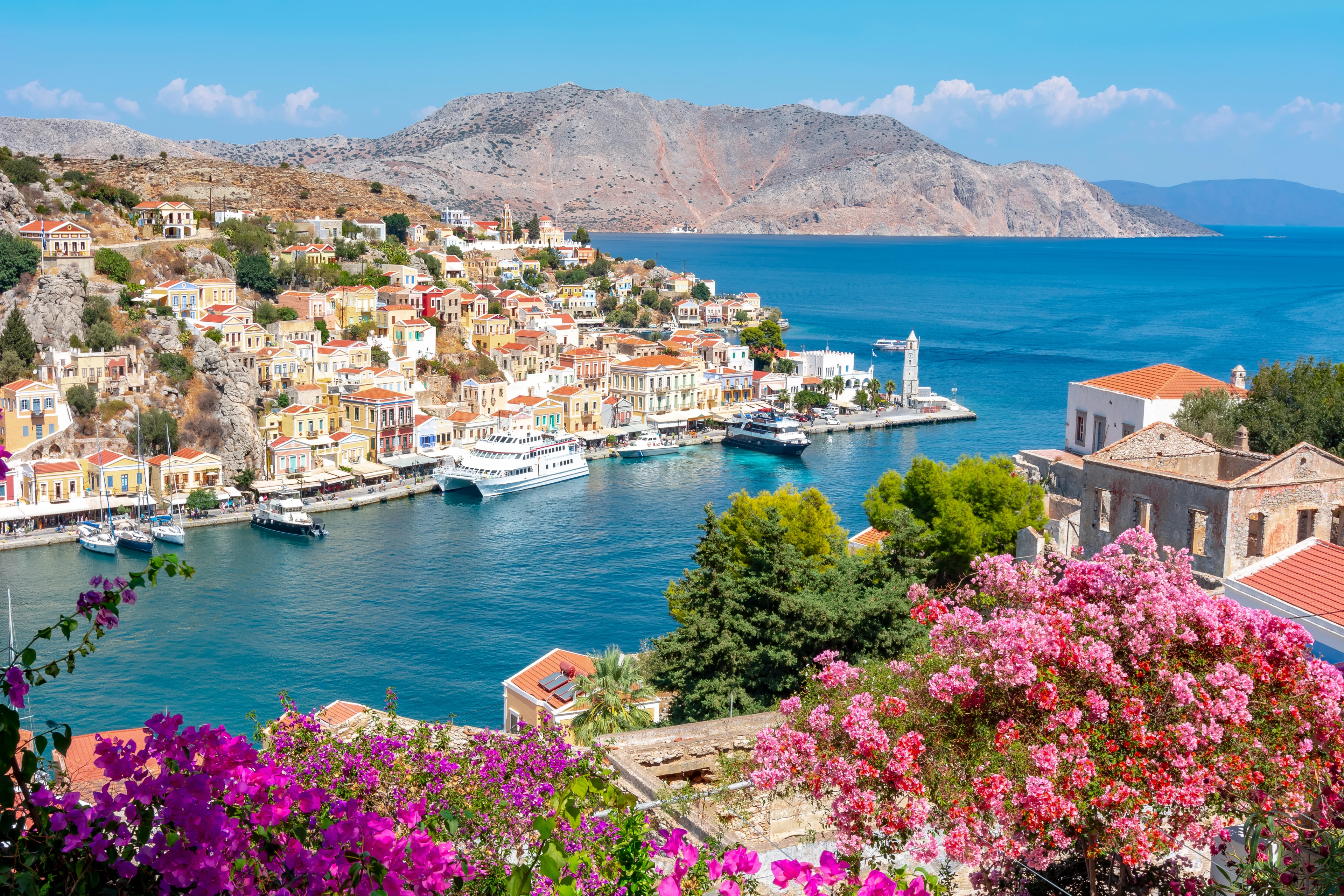 Utsikt över Symi stad, med vackra hus och rosa blommor