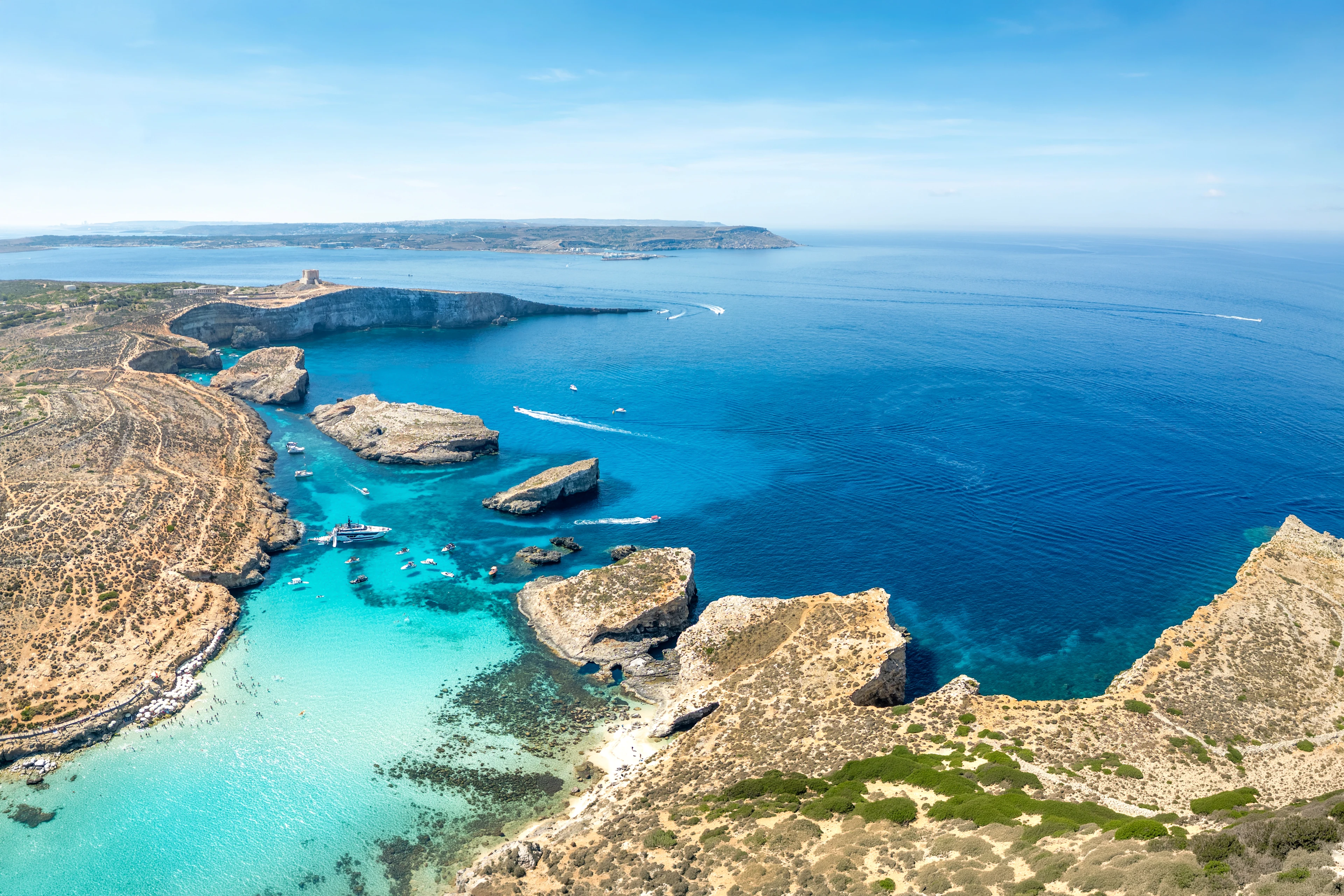 Utsikt över Blue Lagoon på Comino med turkost vatten, klippöar och båtar utanför Maltas kust.