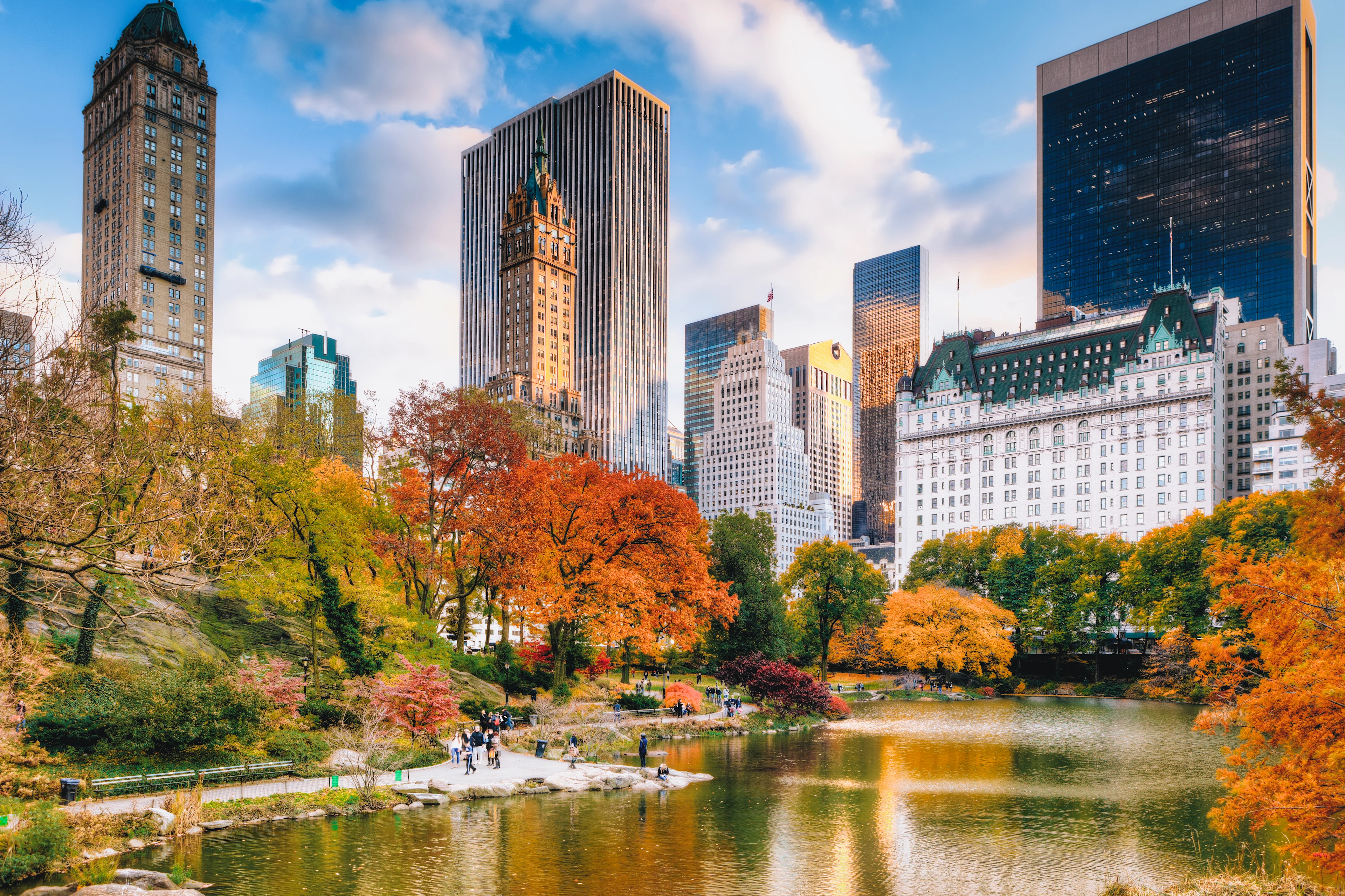 Central Park i New York med trær i høstfarger, en dam og Manhattans skyskrapere i bakgrunnen.