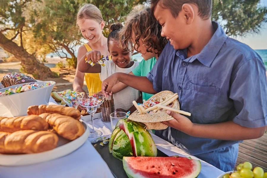 Kinderen plukken eten van een buffet op het strand