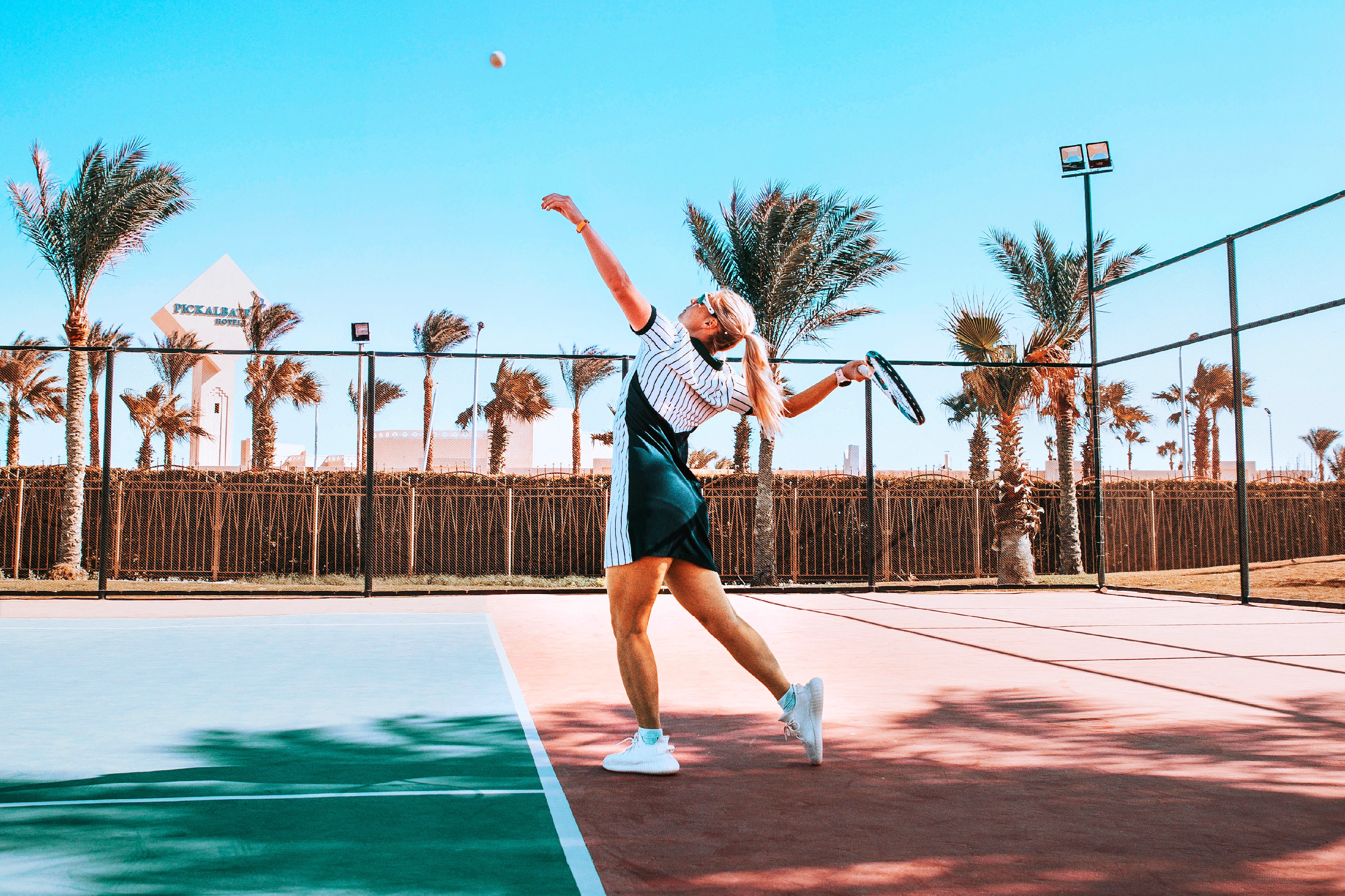 Dame som spiller tennis under palmene