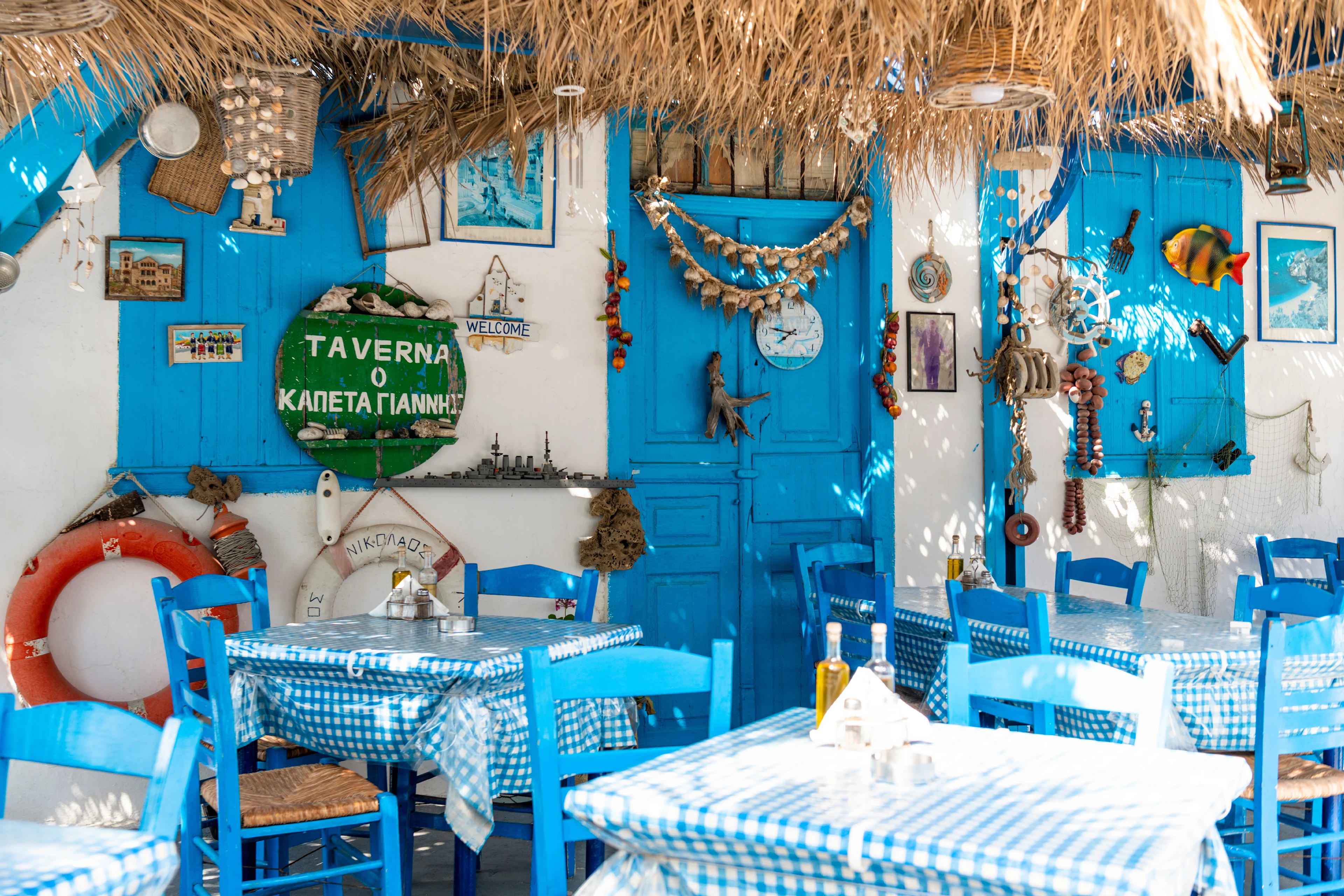 Een traditionele taverna in Finiki op Karpathos met blauwe rieten stoelen, raamkozijnen en deur