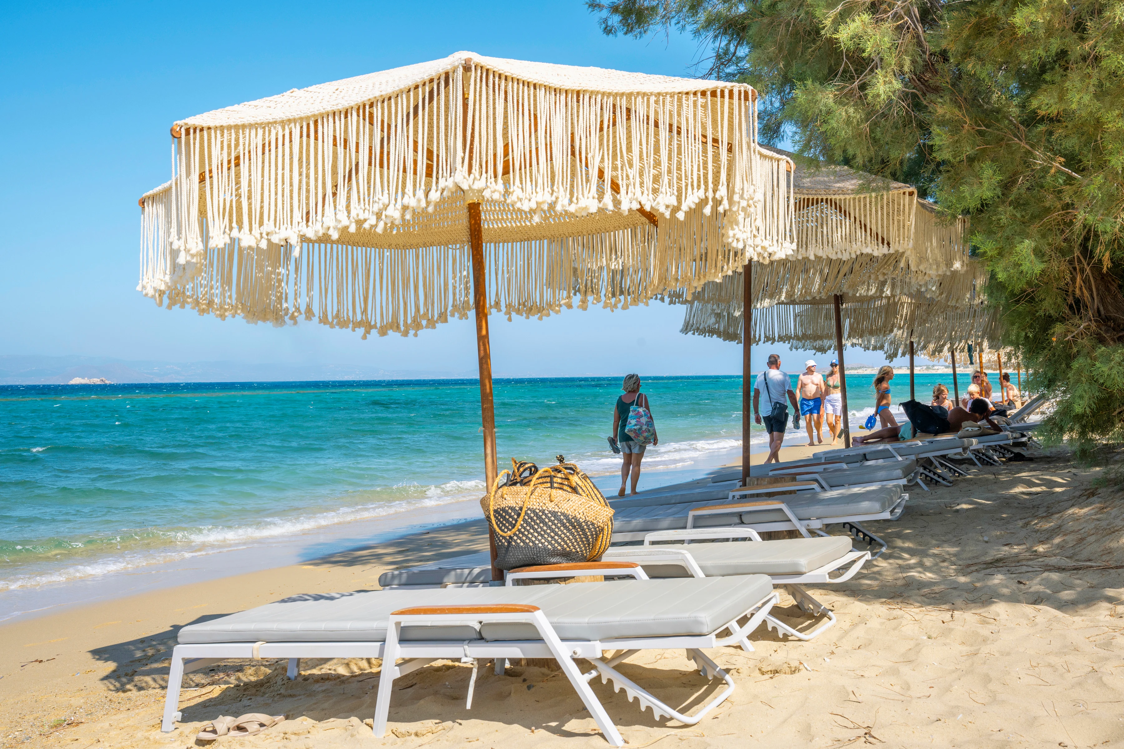En solig sandstrand med parasoller och solstolar på Naxos
