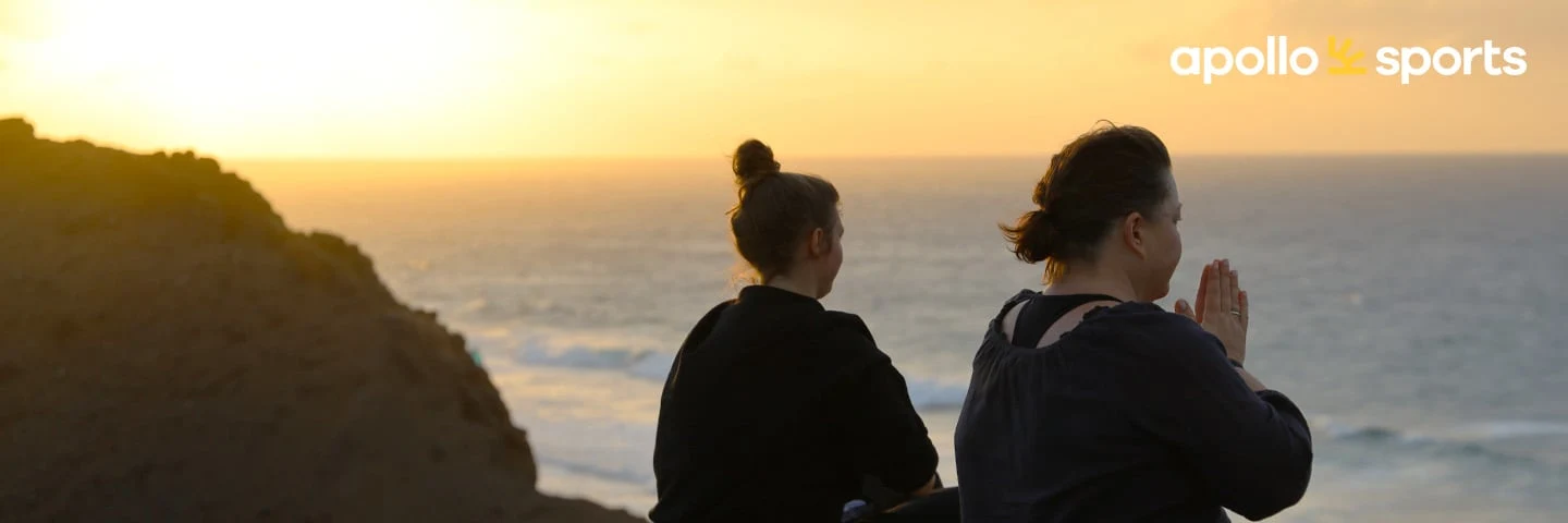 Two women meditating by the ocean